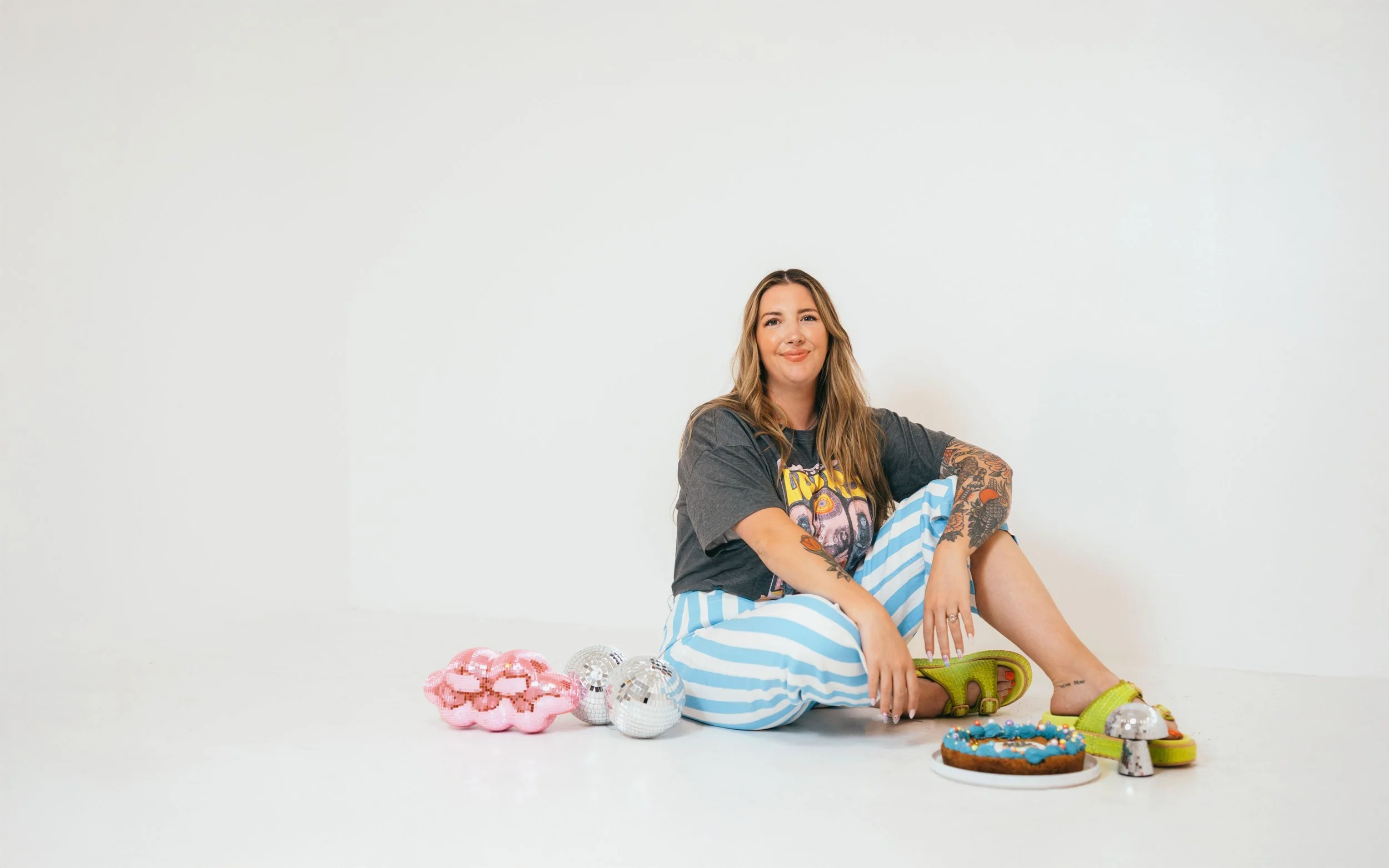 Southern California cookie decorator and home baker sitting on studio floor with her toddler, holding decorated sugar cookies during lifestyle branding session. Candid, personality-driven small business photography for creative mom entrepreneur. Capt
