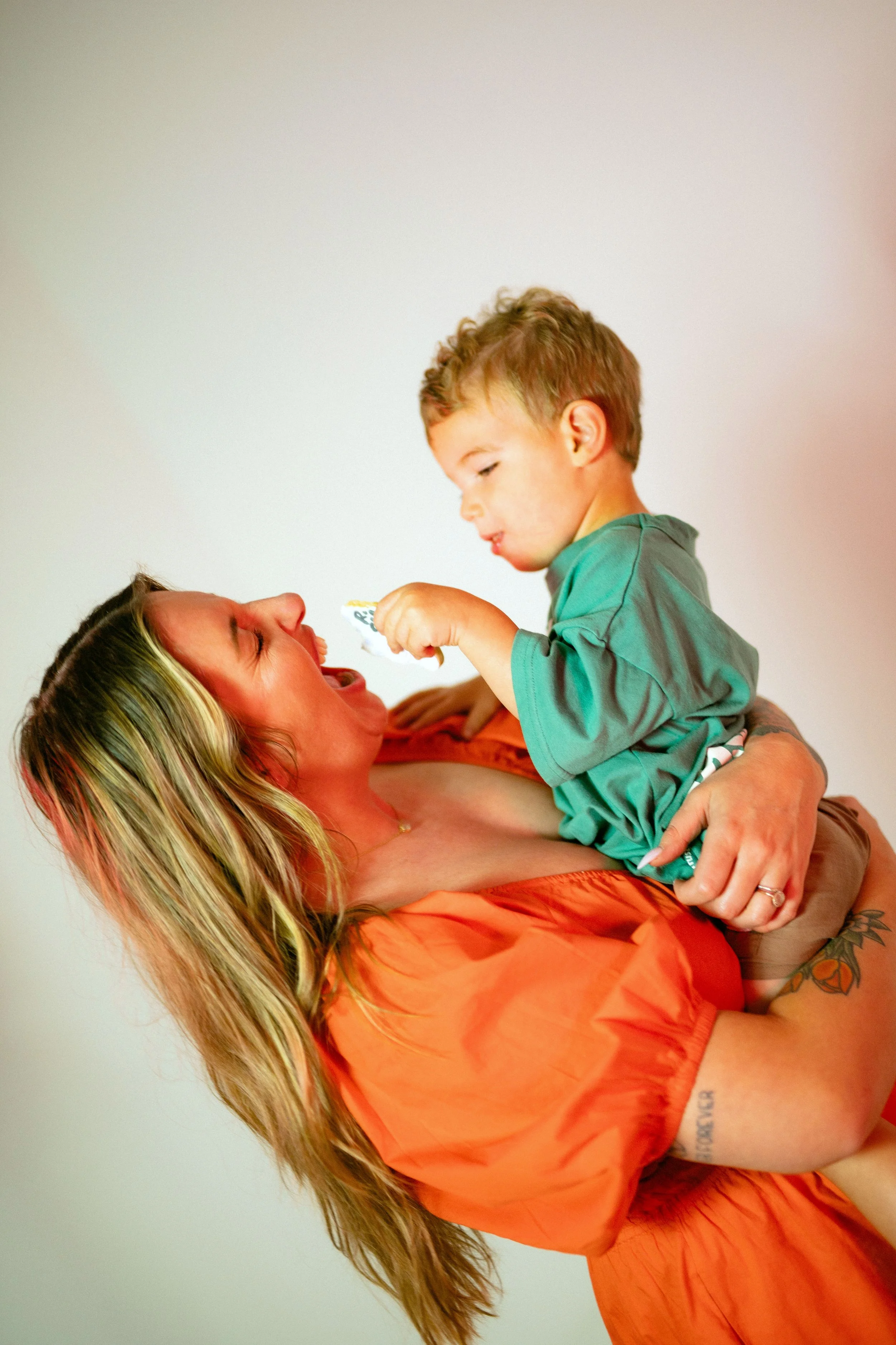 Southern California cookie decorator and home baker holding custom sugar cookie with playful expression during a colorful branding portrait photoshoot. Lifestyle marketing photography highlighting creative small business owner personality, captured b
