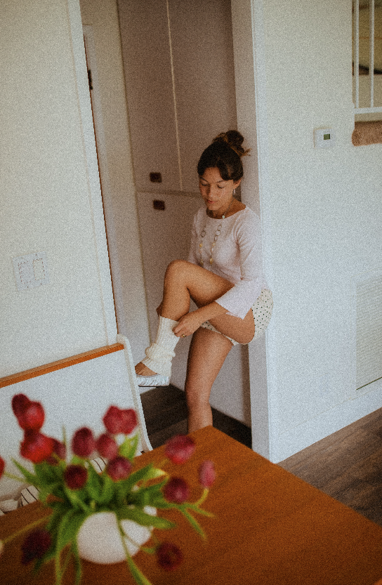Chloe Montoya standing in her doorway in her home in orange county, CA. Creative lifestyle portrait photoshoot- standing ina. fun and unique way in home photoshoot, Wearing, Ballet flats, leg warmers and micro shorts. POsing inspiration for creative 