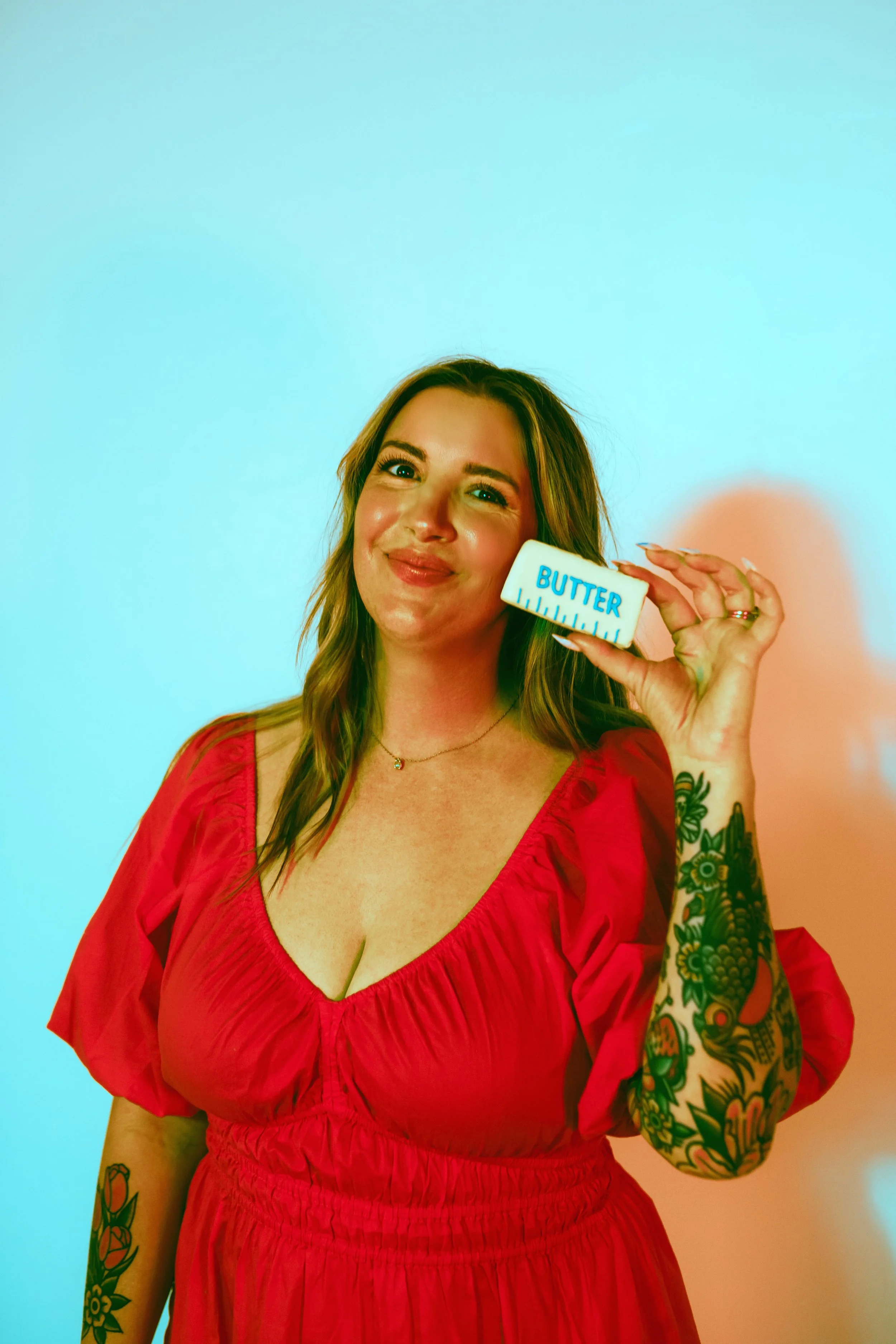 Southern California cookie decorator and home baker holding custom sugar cookie with playful expression during a colorful branding portrait photoshoot. Lifestyle marketing photography highlighting creative small business owner personality, captured b