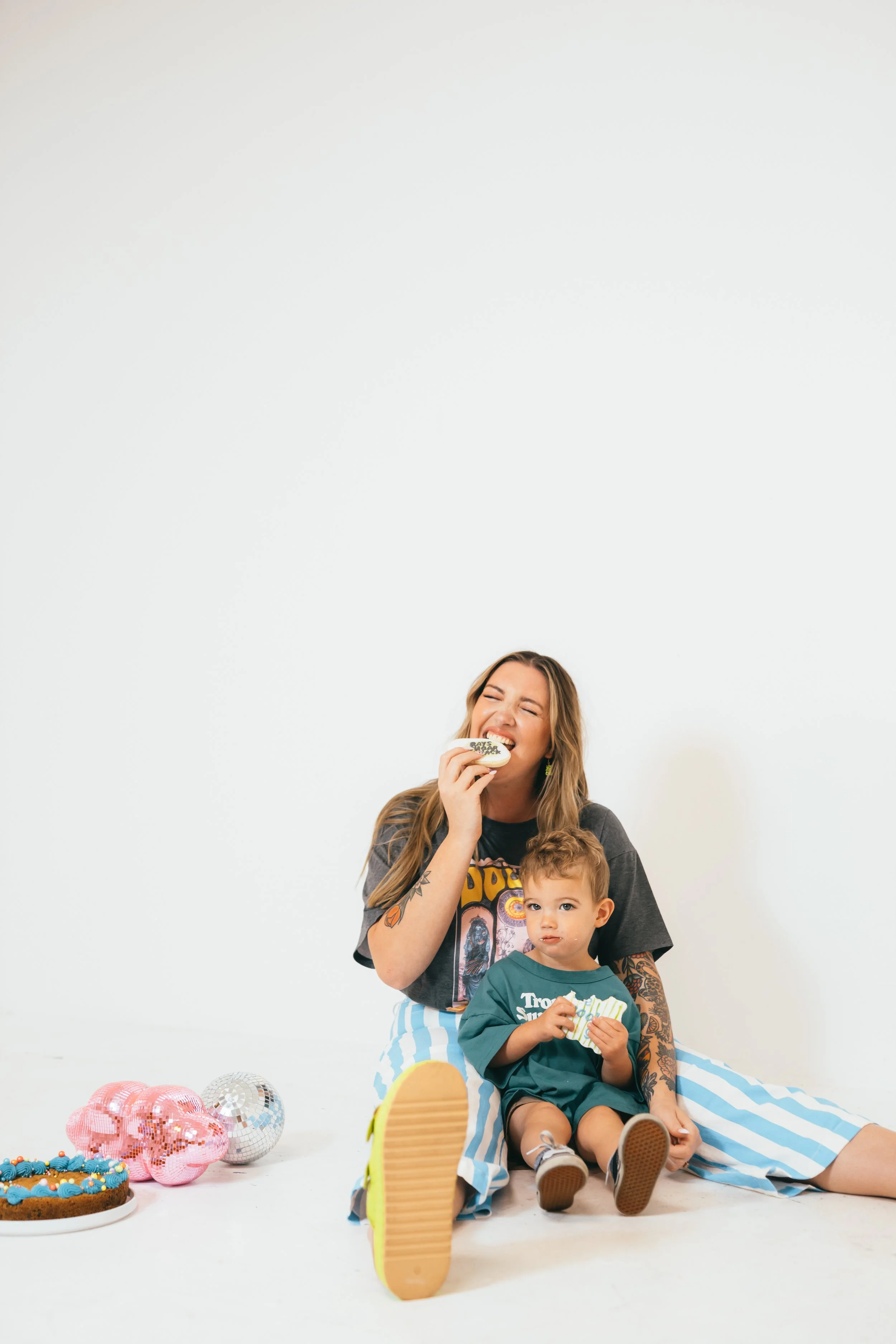 Southern California cookie decorator and home baker holding custom sugar cookie with playful expression during a colorful branding portrait photoshoot. Lifestyle marketing photography highlighting creative small business owner personality, captured b