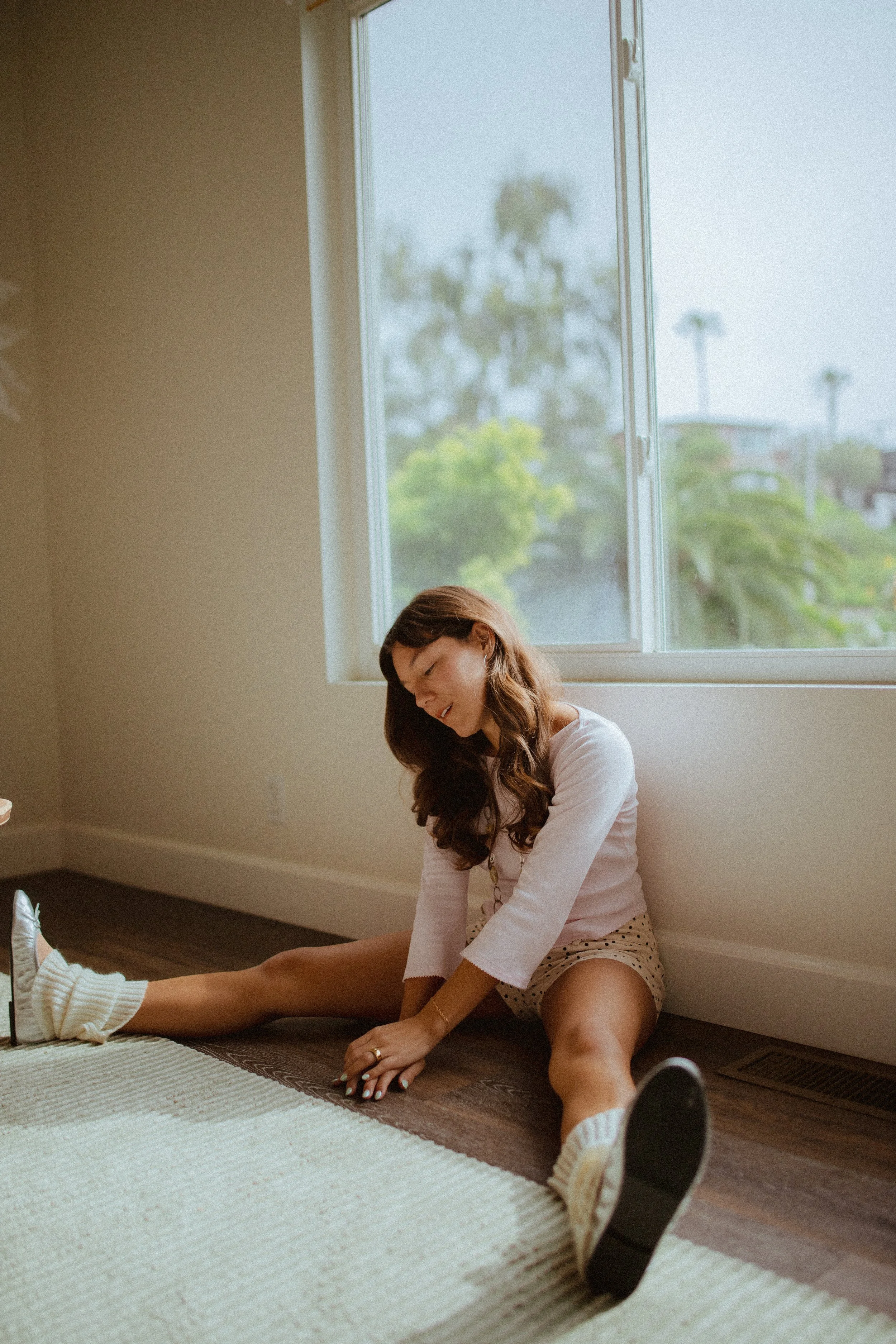 Chloe Montoya sitting on groudn posing in her home in San clemente, CA. Photo taken by southern california lifestyle creative portrait photographer- KElsie Carlson. Model sitting by window, posing inspiration, girly fem outfit inspiration