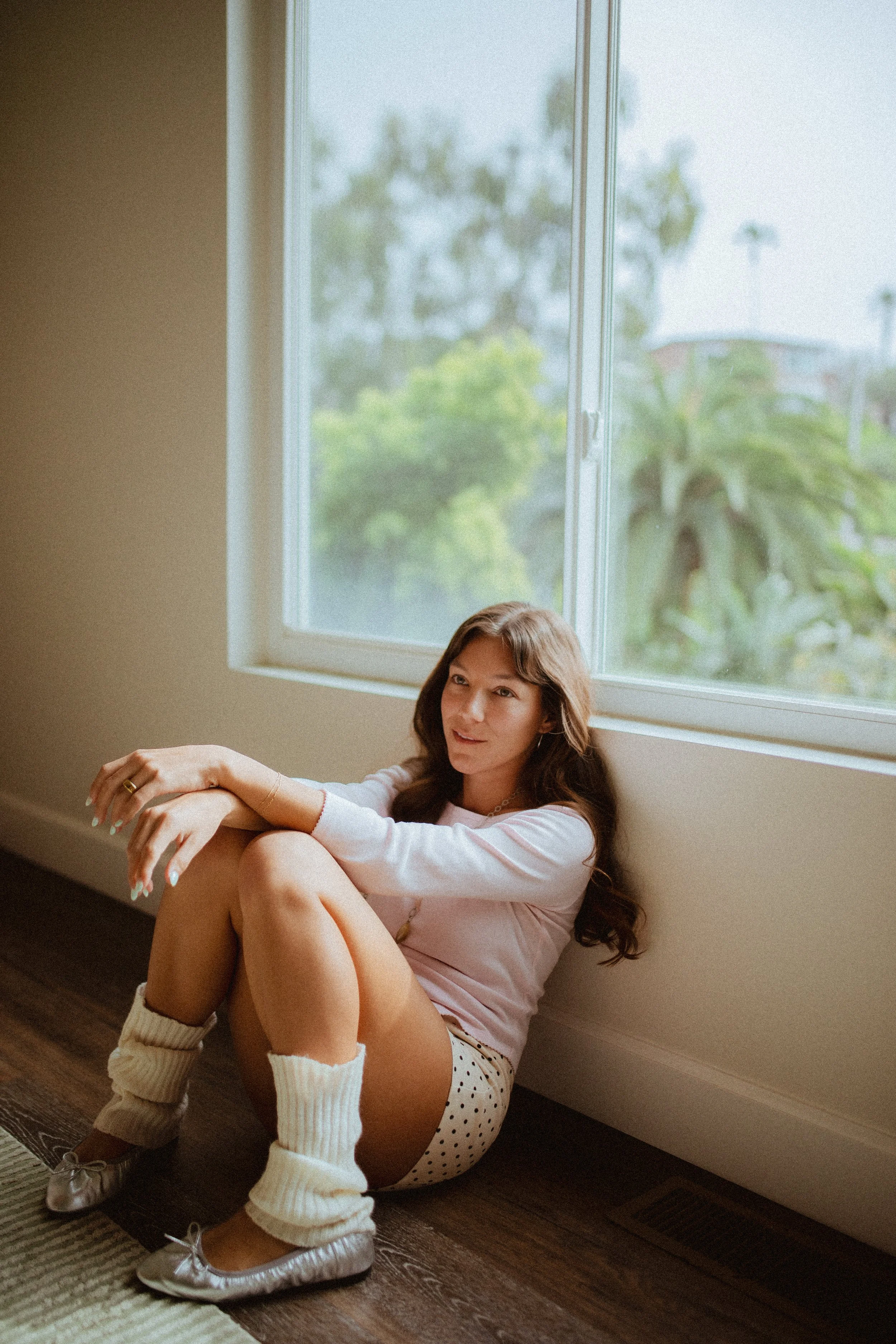 Chloe Montoya sitting on groudn posing in her home in San clemente, CA. Photo taken by southern california lifestyle creative portrait photographer- KElsie Carlson. Model sitting by window, posing inspiration, girly fem outfit inspiration