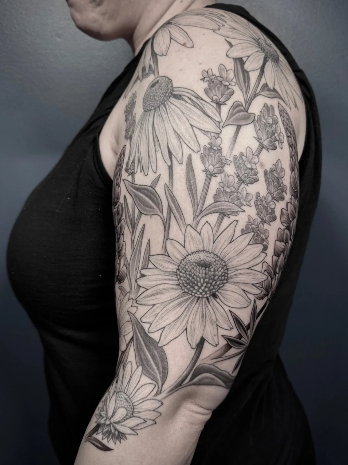 Fine line black and grey hand half sleeve tattoo with flowers and leaves, created by Seattle tattoo artist Eli Bischof