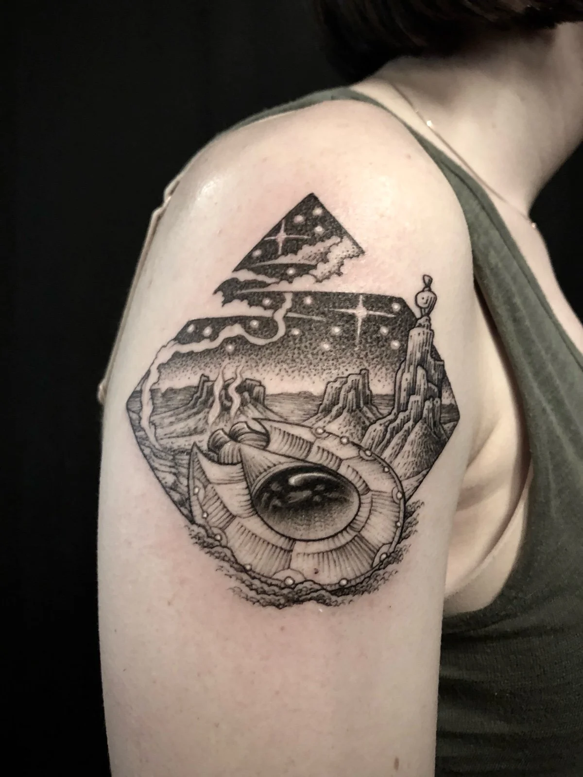 A fine line and black and grey tattoo with dotwork shading of a desert landscape at night, with a UFO crash, created by Seattle tattoo artist Eli Bischof.