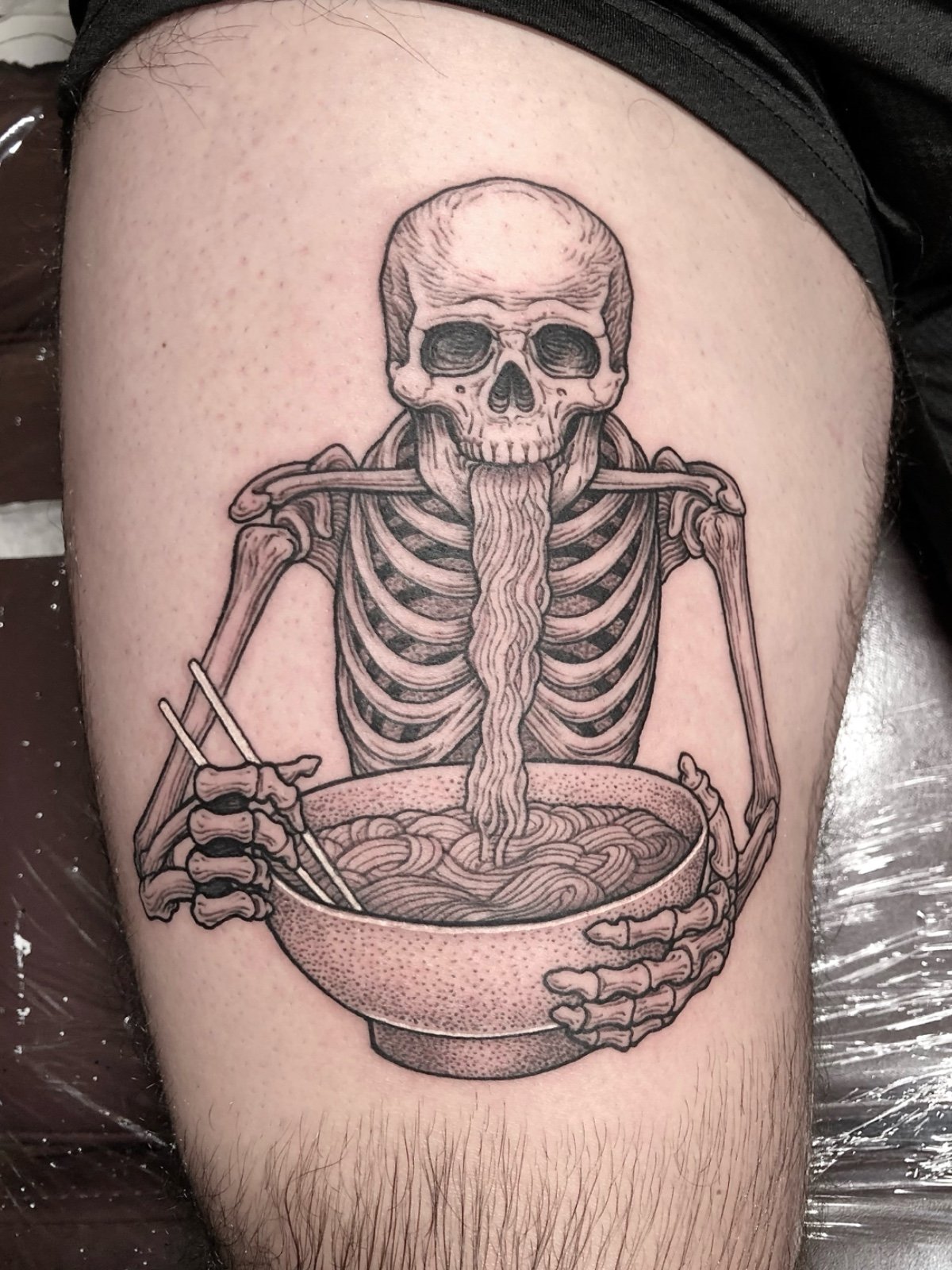 Fine line black and grey skeleton eating ramen with chopsticks tattoo, created by Seattle tattoo artist Eli Bischof.