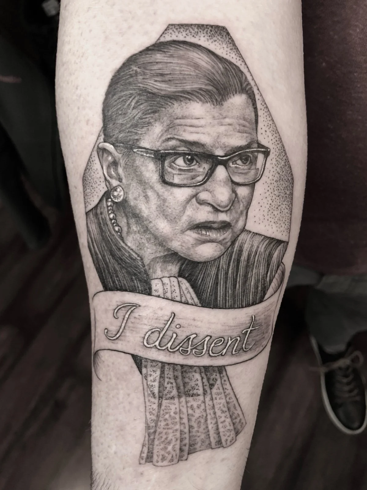 Fine line and black and grey celebrity tattoo portrait of Ruth Bader Ginsburg with the words, "I dissent", created by Seattle tattoo artist Eli Bischof.