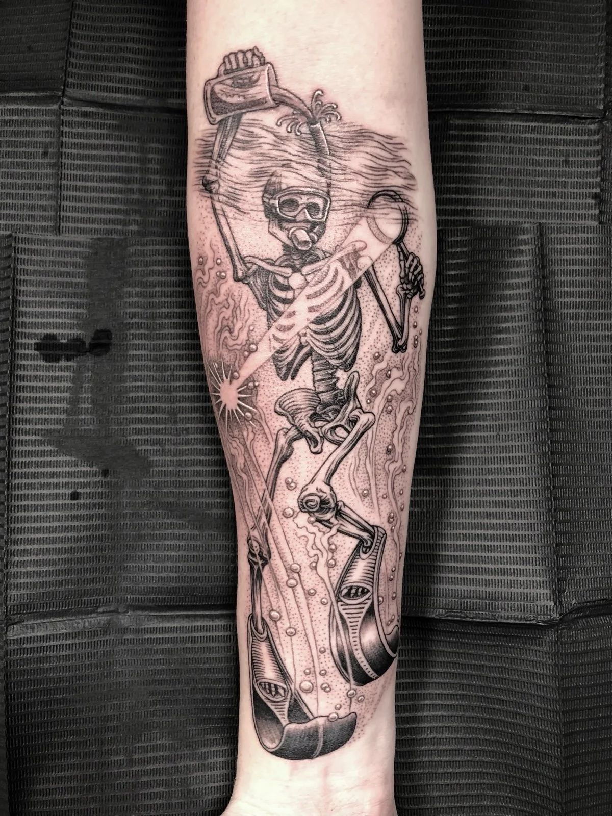 Fine line black and grey tattoo of a snorkeling skeleton who is pouring beer down his snorkel, created by Seattle tattoo artist Eli Bischof.