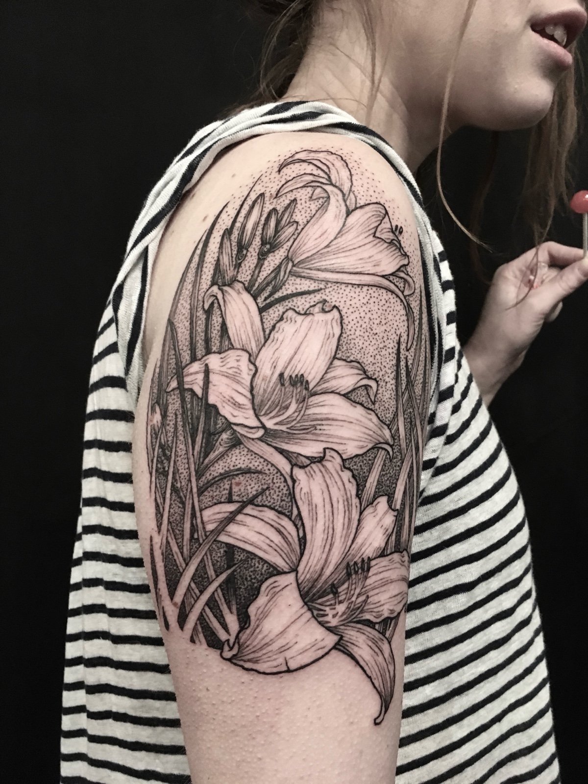 Fine line black and grey shoulder tattoo, with lilies and leaves in an art nouveau influenced style, created by Seattle tattoo artist Eli Bischof