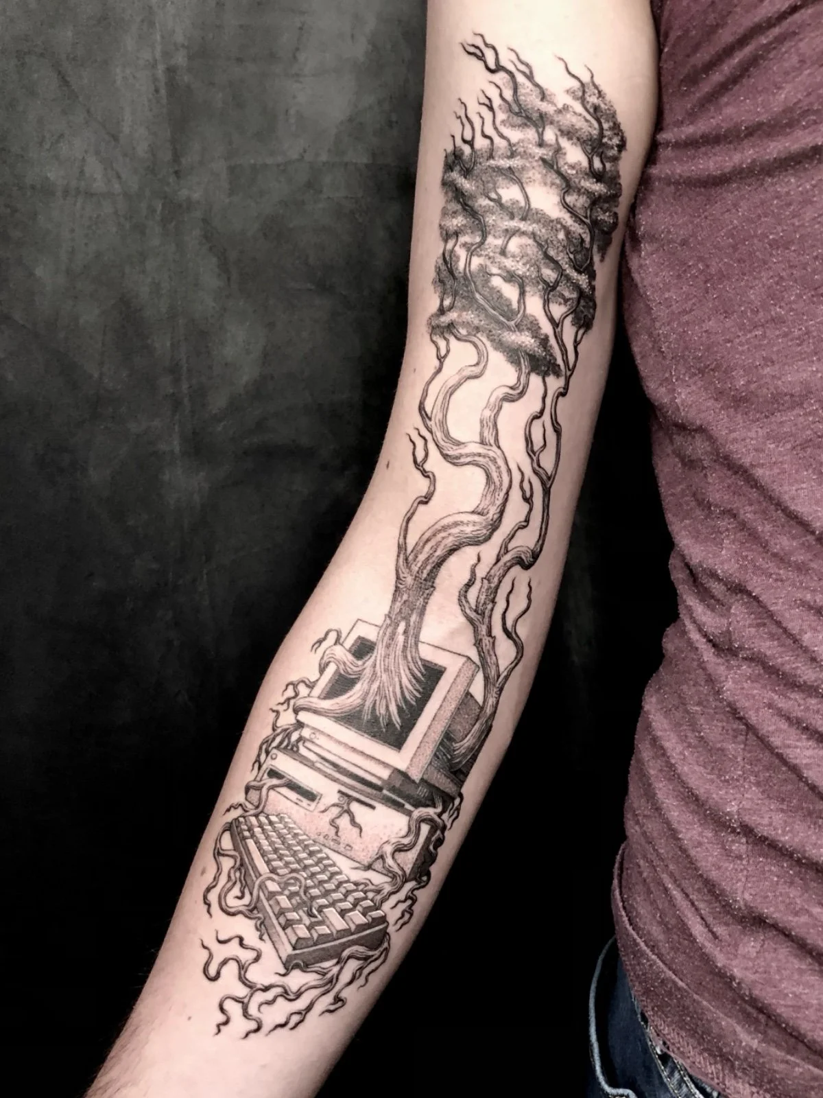 A fine line and black and grey tattoo of a tree growing out of the screen of a vintage computer, created by Seattle tattoo artist Eli Bischof.
