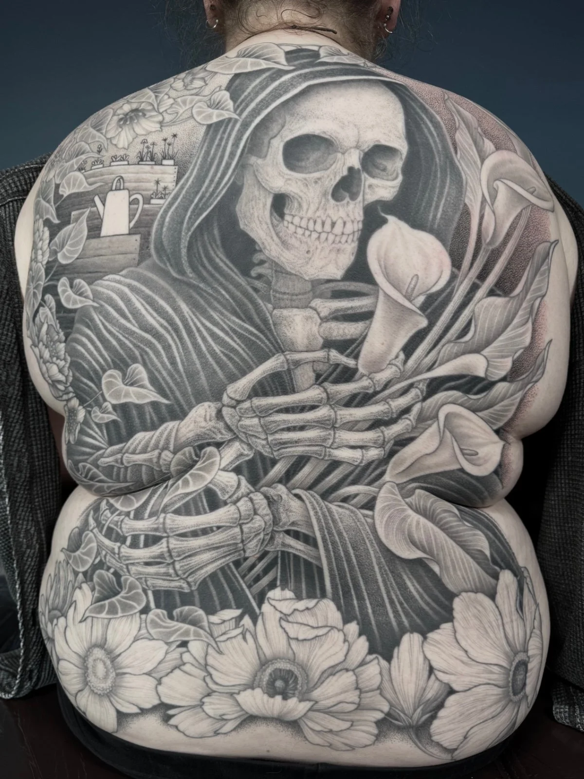 Fine line black and grey black work back piece tattoo of a grim reaper holding flowers in a garden, created by Seattle tattoo artist Eli Bischof.