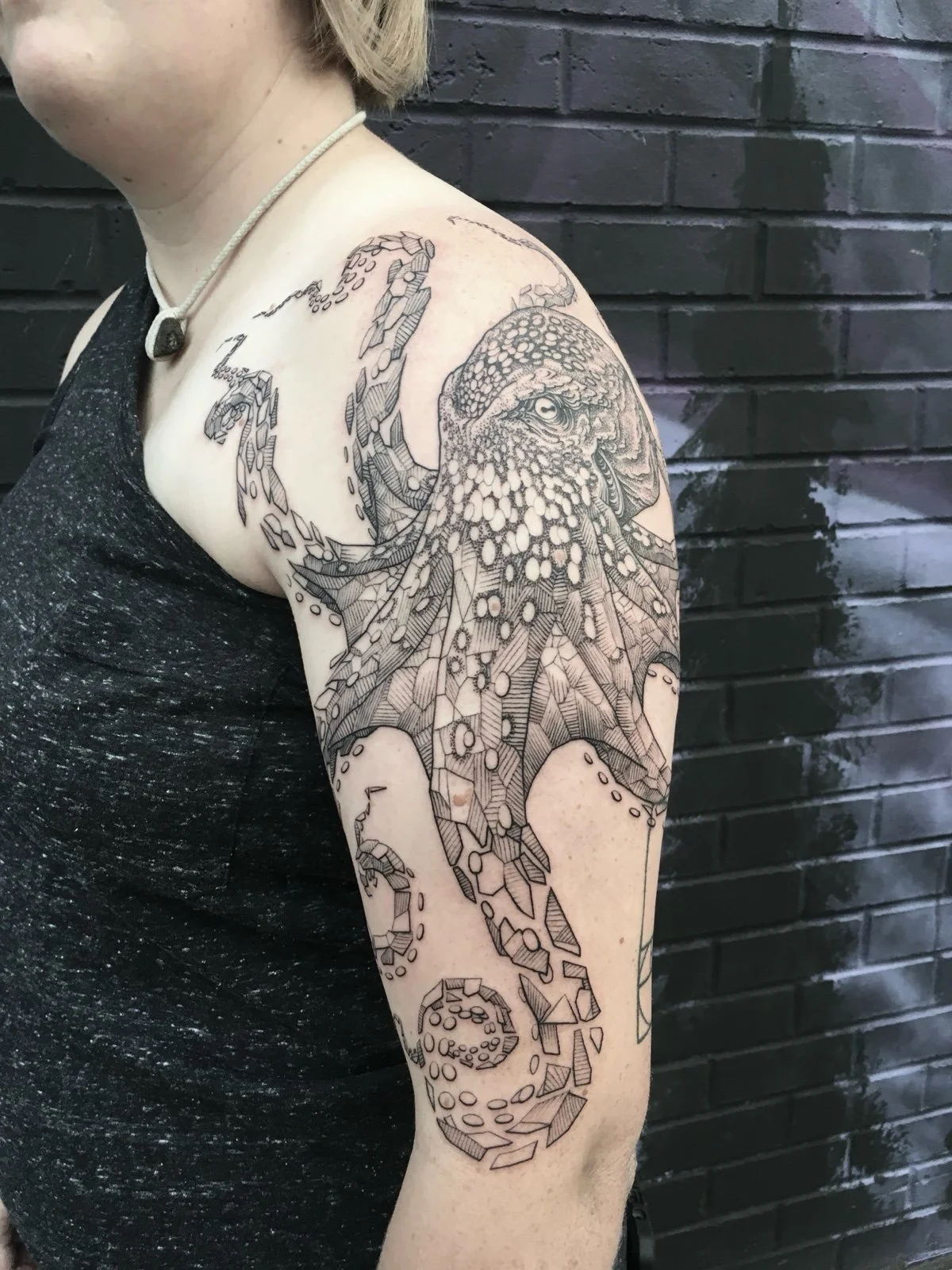 An illustrative tattoo of an octopus, with stipple, dotwork, and linear shading. The octopus tattoo is designed with geometric shards breaking away. The tattoo was made by Eli Making Stuff in Seattle.