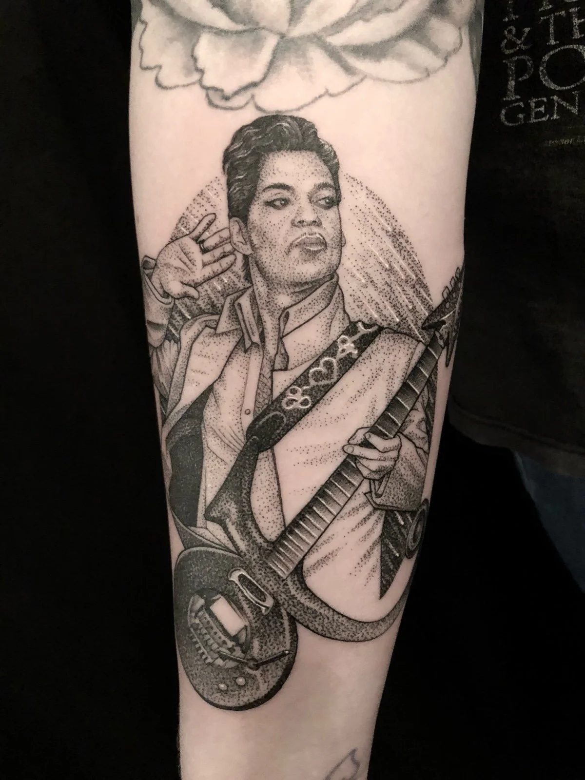 Fine line and black and grey celebrity tattoo portrait of the Artist Formerly Known as Prince, playing his guitar in a rainstorm, created by Seattle tattoo artist Eli Bischof.