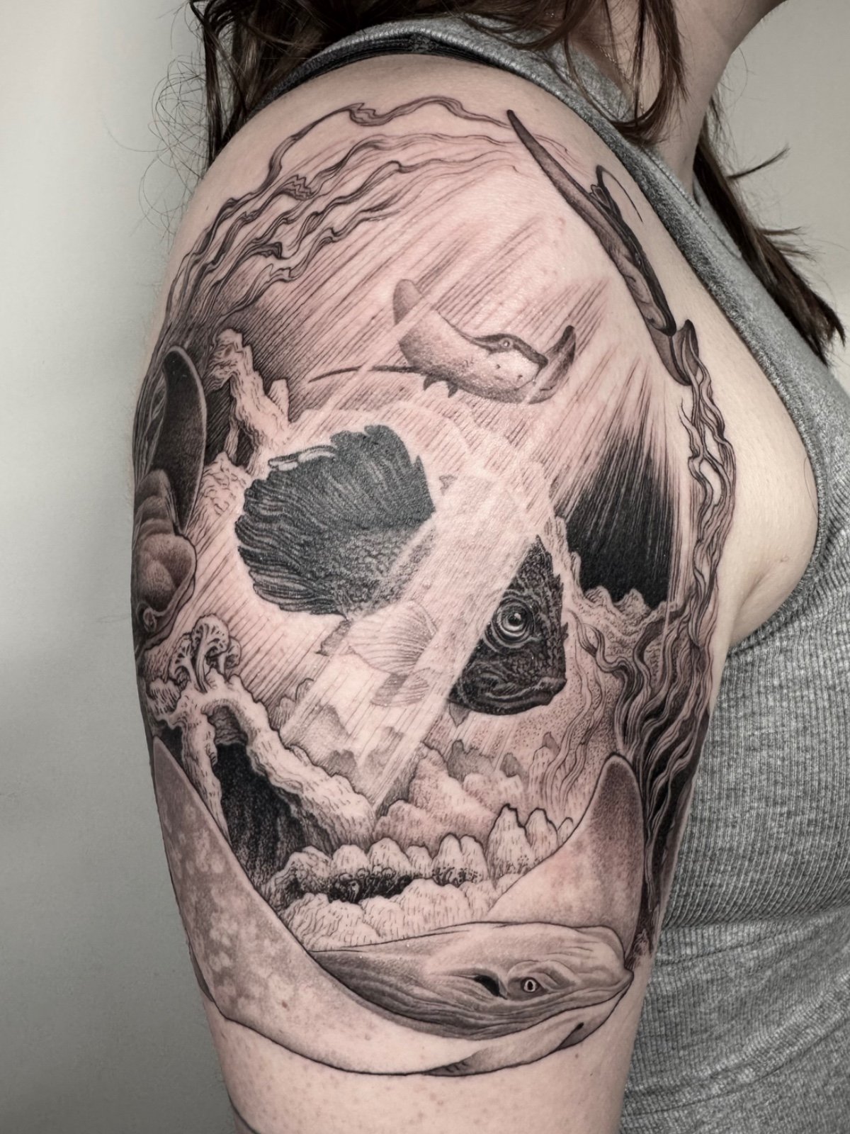 Fine line black and grey skull illusion tattoo, consisting of an underwater scene featuring stingrays, fish, and kelp, created by Seattle tattoo artist Eli Bischof.