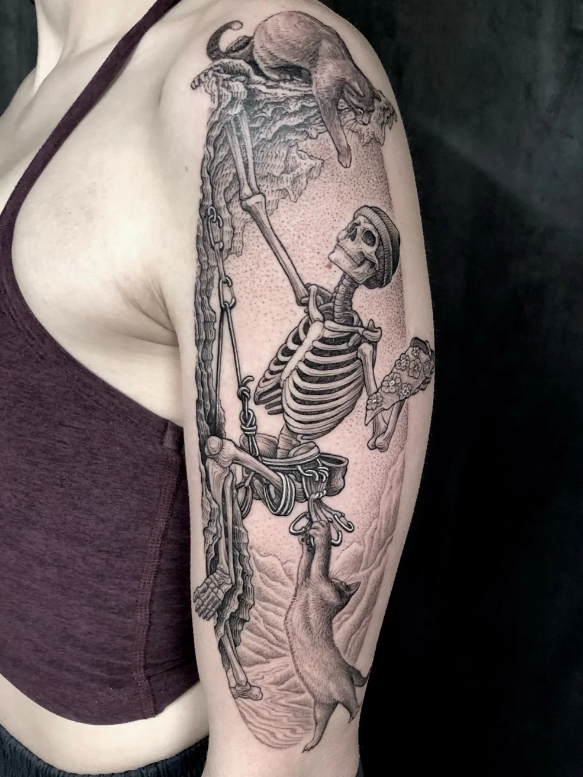 Fine line black and grey whimsical tattoo of a skeleton rock climbing with cats and pizza, created by Seattle tattoo artist Eli Bischof.