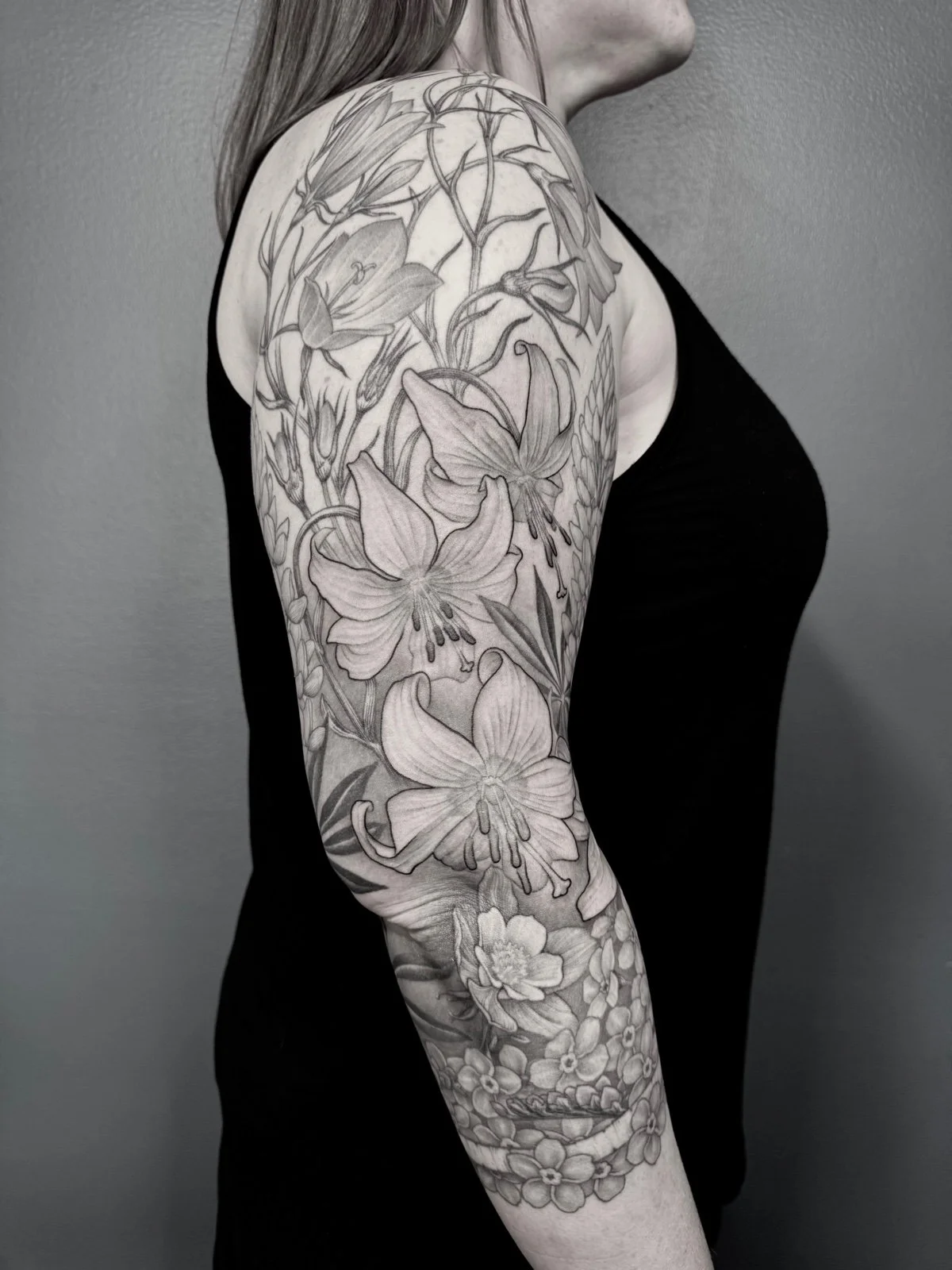 Fine line black and grey sleeve tattoo, with flowing flower arrangement, created by Seattle tattoo artist Eli Bischof