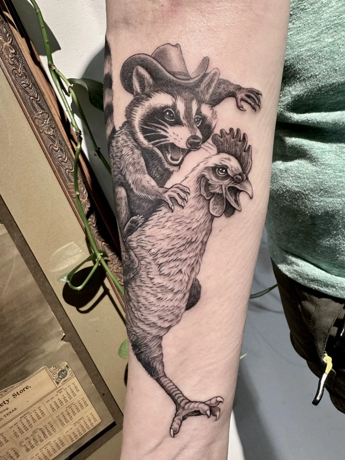 A fine line whimsical tattoo of a cowboy raccoon riding a chicken, created by Seattle tattoo artist Eli Bischof.
