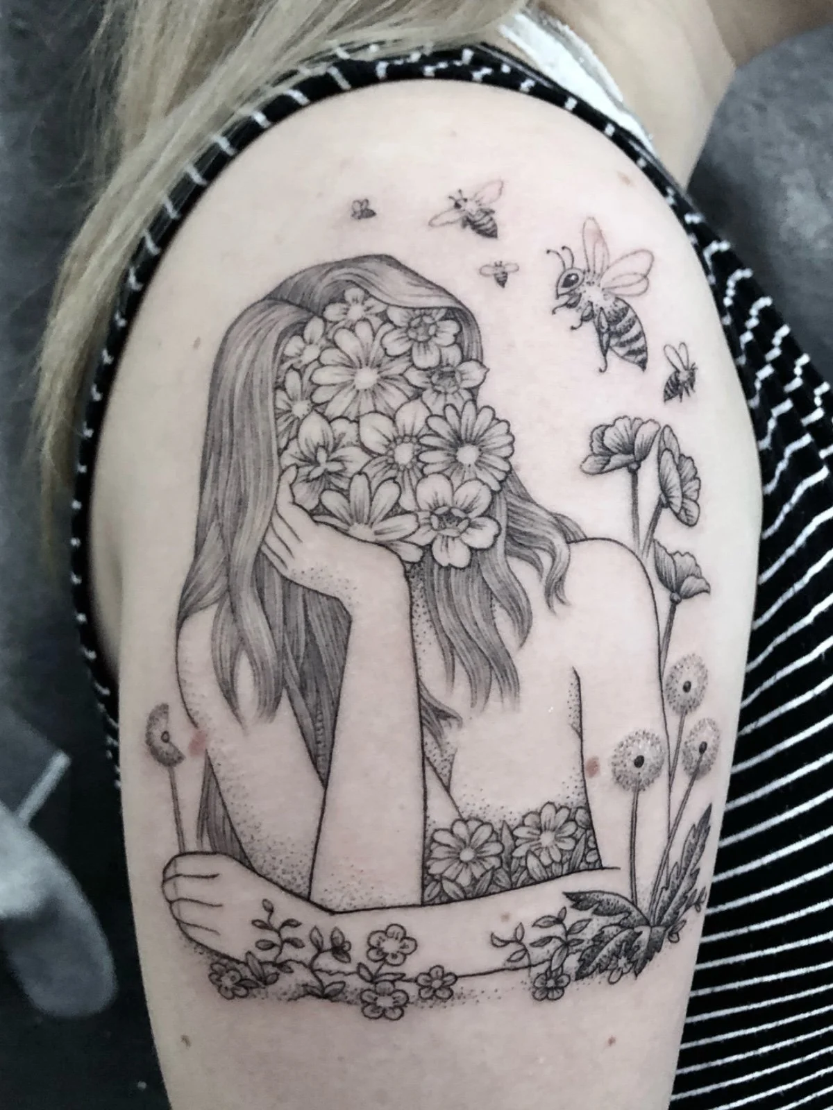 Fine line tattoo of woman with floral face, with flowers and bees, created by Seattle tattoo artist Eli Bischof.