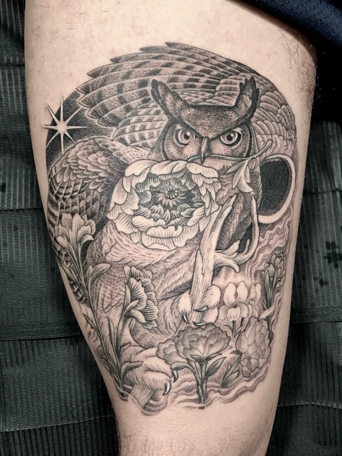 Fine line black and grey skull illusion tattoo, consisting of a great horned owl with flowers, created by Seattle tattoo artist Eli Bischof.