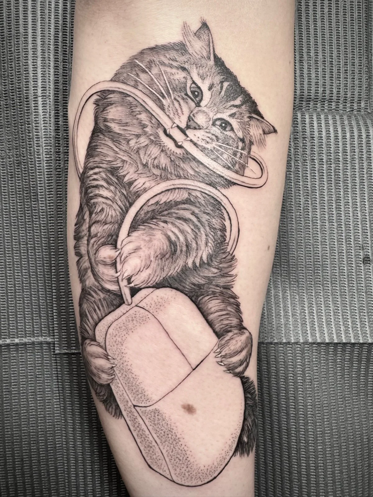 Fine line and black and grey whimsical pet portrait tattoo of a cat wrestling with a vintage computer mouse, created by Seattle tattoo artist Eli Bischof.