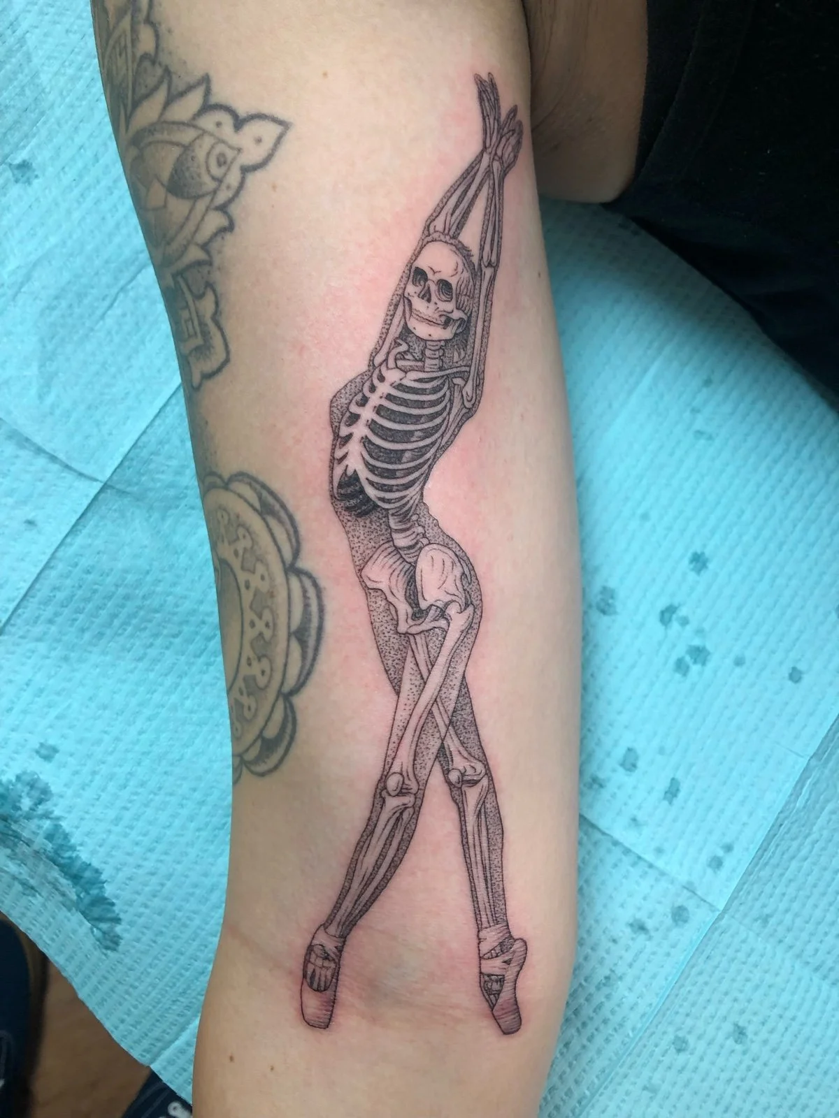 Fine line black and grey bicep tattoo of ballerina skeleton, created by Seattle tattoo artist Eli Bischof.