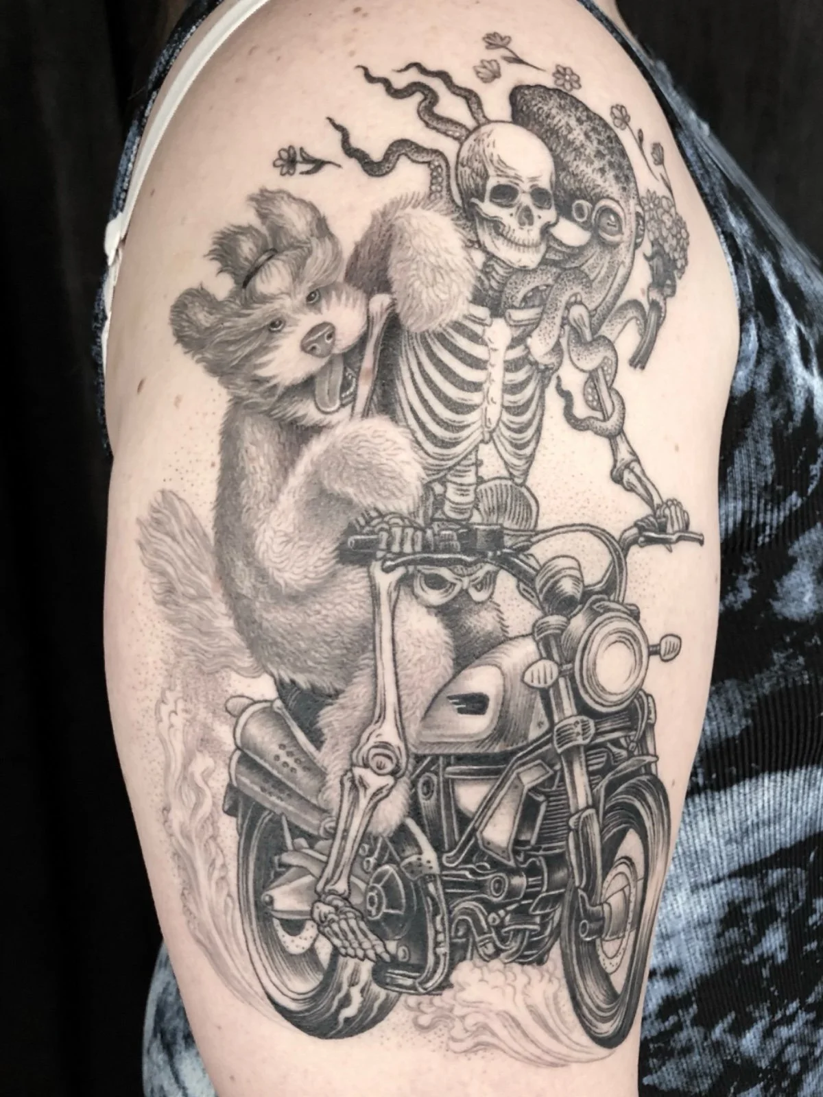 Healed fine line black and grey whimsical tattoo of a skeleton riding a motorcycle with a dog and octopus friends, created by Seattle tattoo artist Eli Bischof.