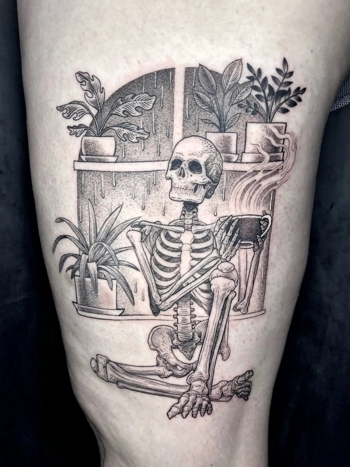 Fine line black and grey tattoo of a skeleton drinking coffee and cozy indoors on a rainy day, with houseplants, created by Seattle tattoo artist Eli Bischof.