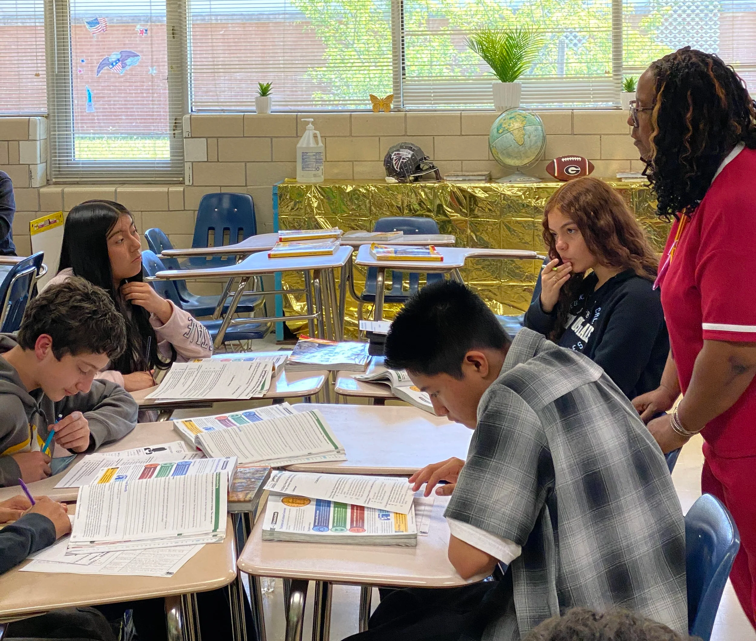An educator works with a group of students who are all pacing through work independently.