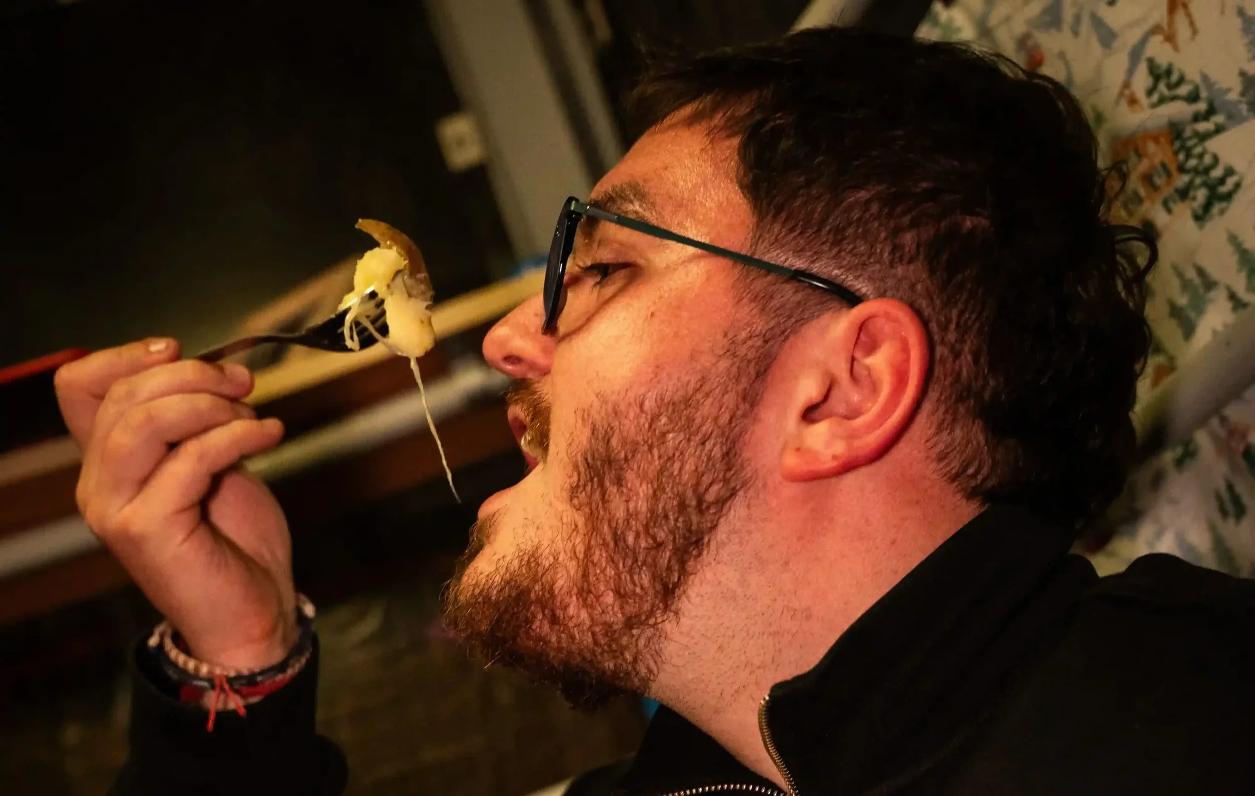 Un homme avec des lunettes mange des pâtes à la fourchette au restaurant.