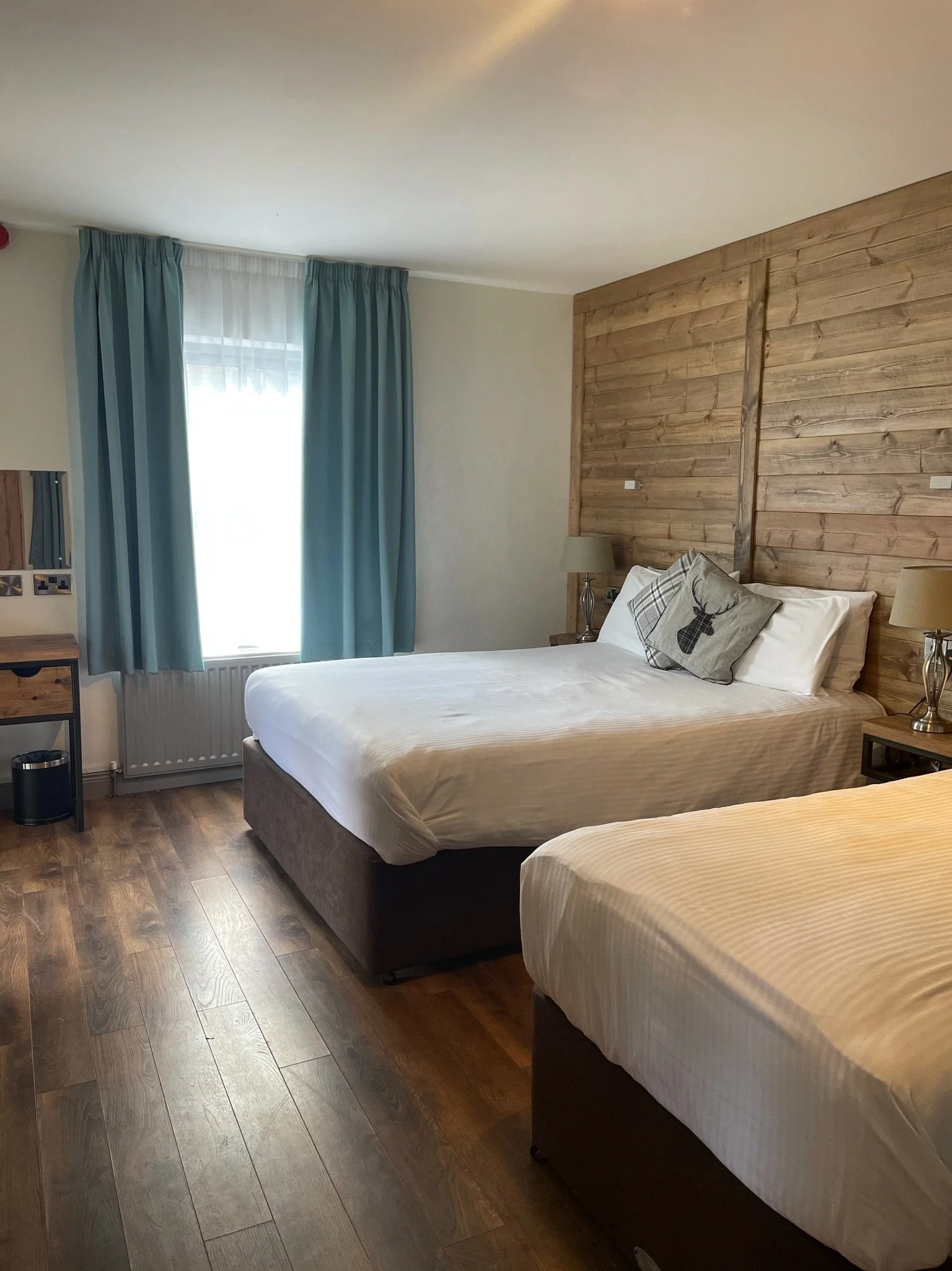 A bedroom layout at Lusty Beg Island Resort with wood paneled walls, wooden floor and two separate beds.