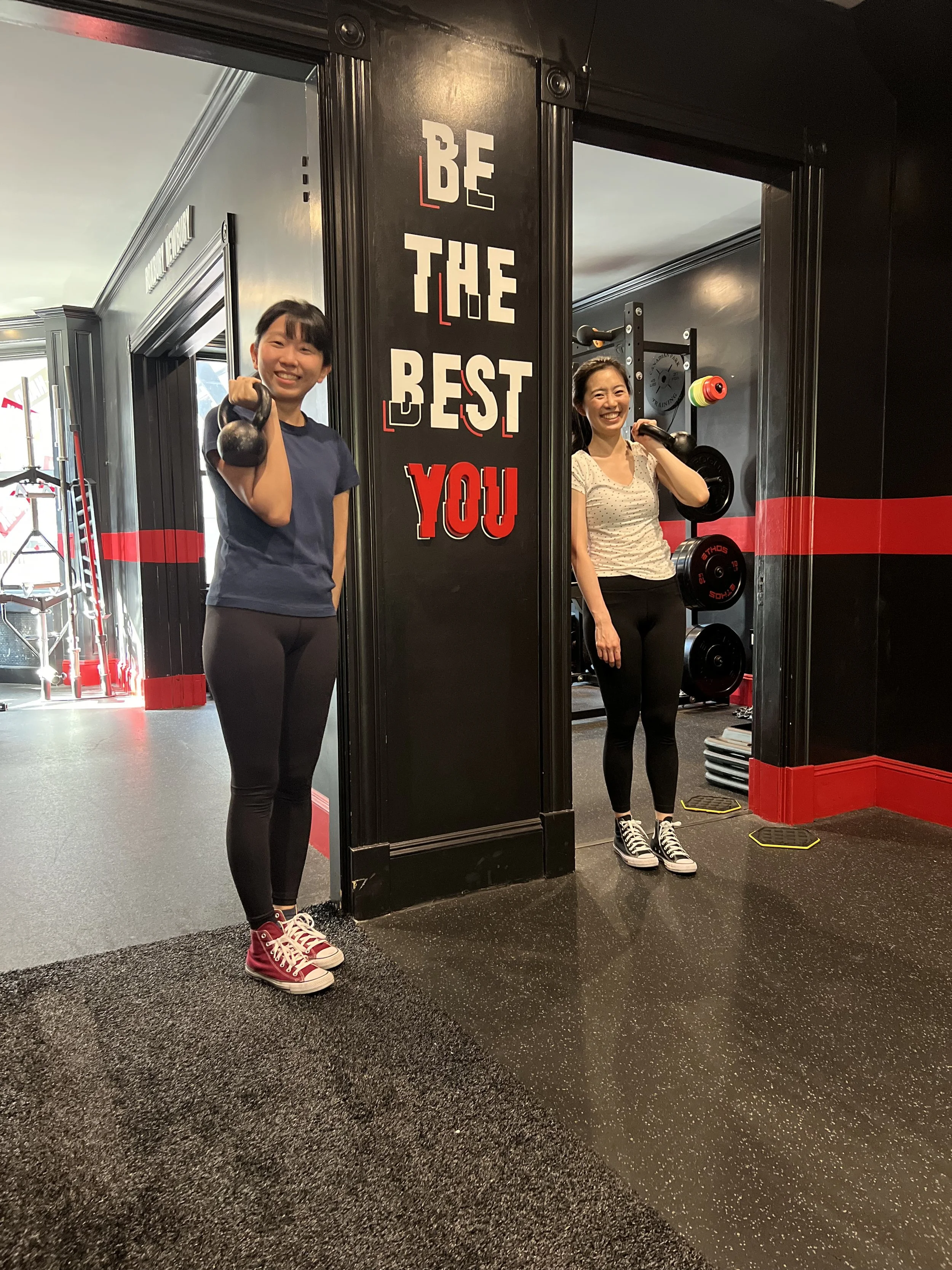 Two Asian women performing kettlebell exercises during a small group fitness class at Canadian Park Training in Boston