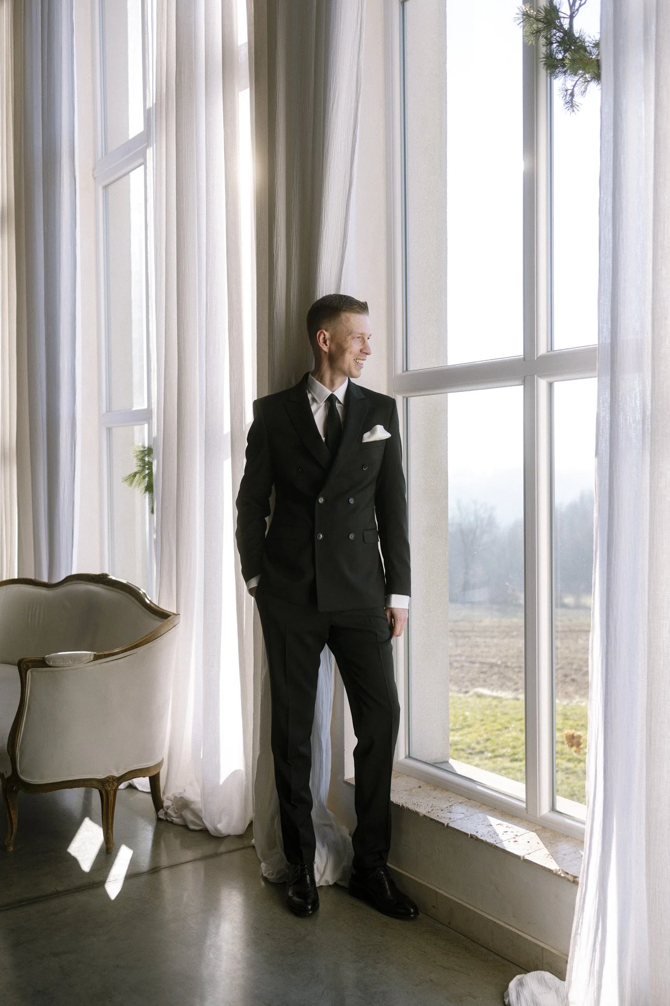 groom standing close to the window at villa love