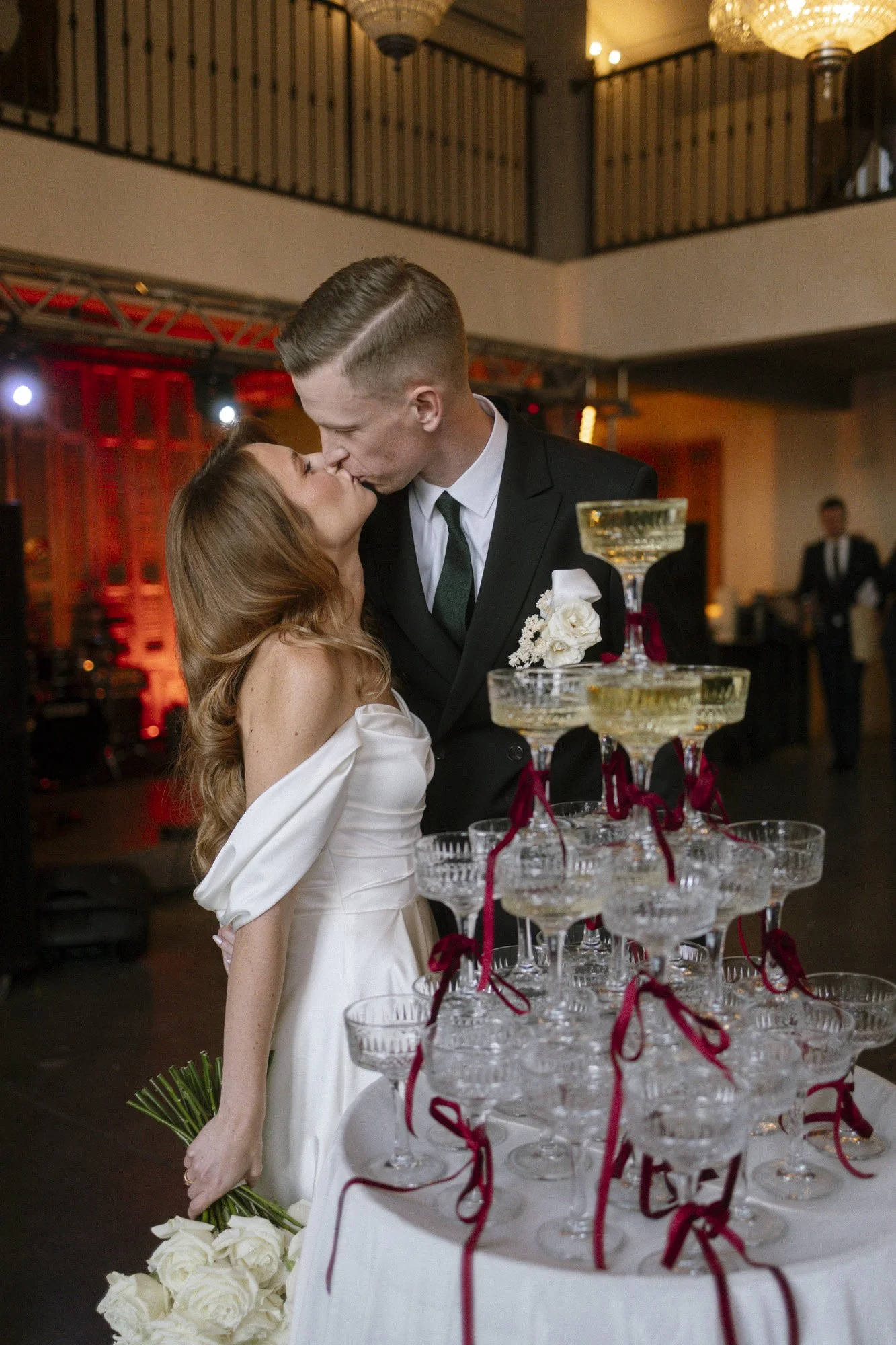bride and groom kissing behind champagne tower during reception at villa love