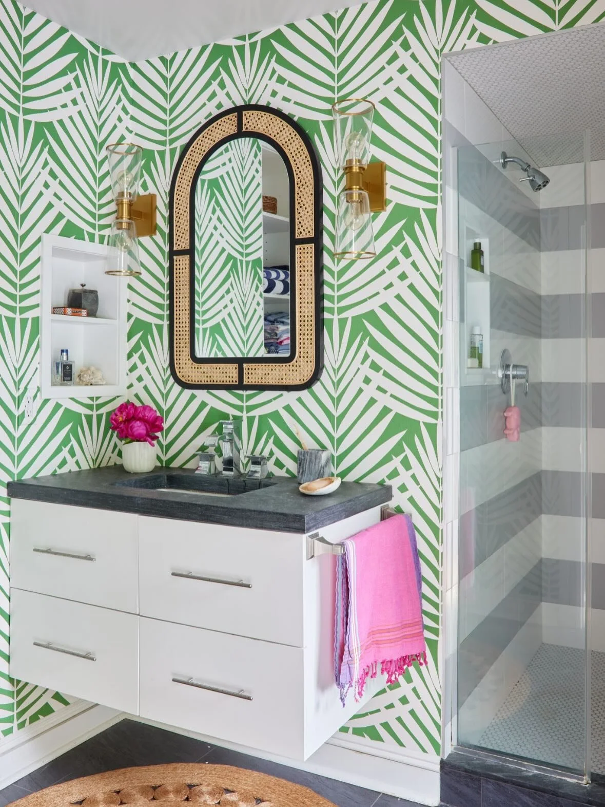 Same bathroom: still bright, clean, and tailored.

Before: crisp, calming, and quietly chic.

After: that same fresh foundation, now with a little wink 😉 graphic palm (vinyl) wallpaper for energy, warm brass for glow, and a cane-detailed mirror that