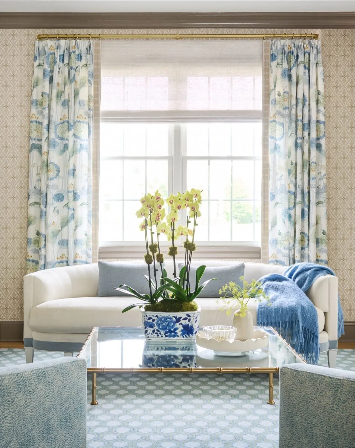 Proof that the right drapery can transform a space. This formal living room went from dark and a bit mismatched to light, bright, and fully pulled together, with elegant panels framing the windows, a fresh wallcovering bringing in pattern, and refine