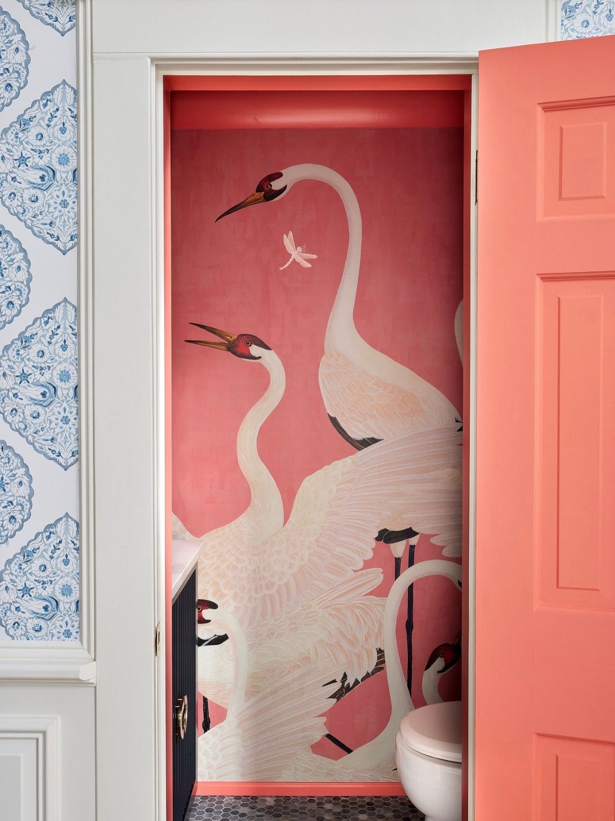 The assignment? Make this jewel box of a powder room whimsical, bold and a bit unexpected. A sweeping @gucci heron mural wraps the walls, while coral lacquer trim, brass accents and pitch black vanity keep it tailored. Proof that the smallest rooms c