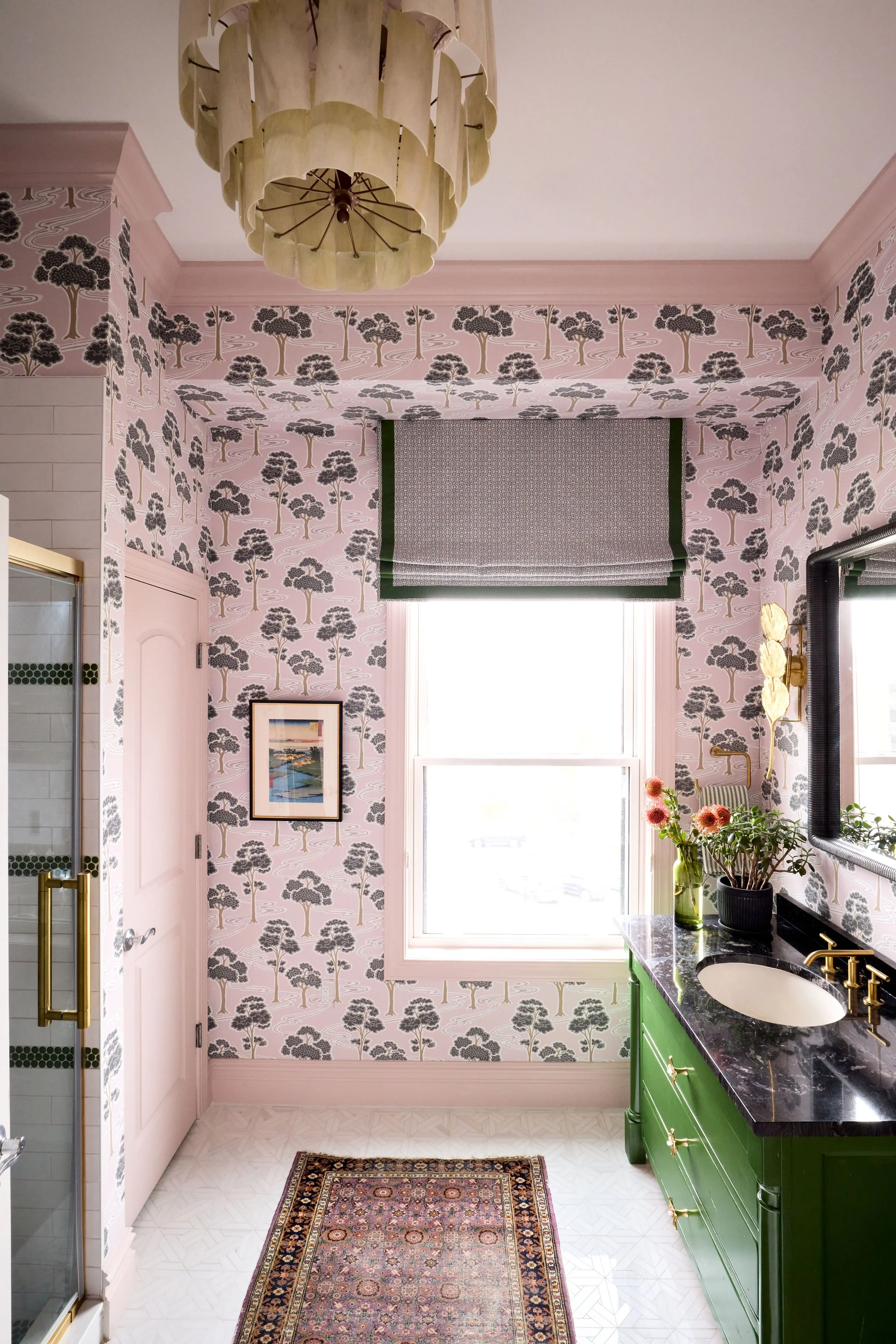 a vibrant bathroom with Schumacher wallpaper and roman shade. A glossy green vanity