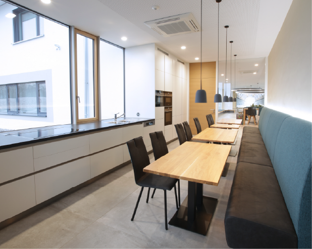 Pause
Zur Begegnung, Entspannung, Kommunikation, der Bereitung und dem Verzehr gemeinsamer Mahlzeiten dient der zentrale, die einzelnen Gebäude verbindende, Baukörper mit großer Küche und variantenreichen Sitzmöglichkeiten. 