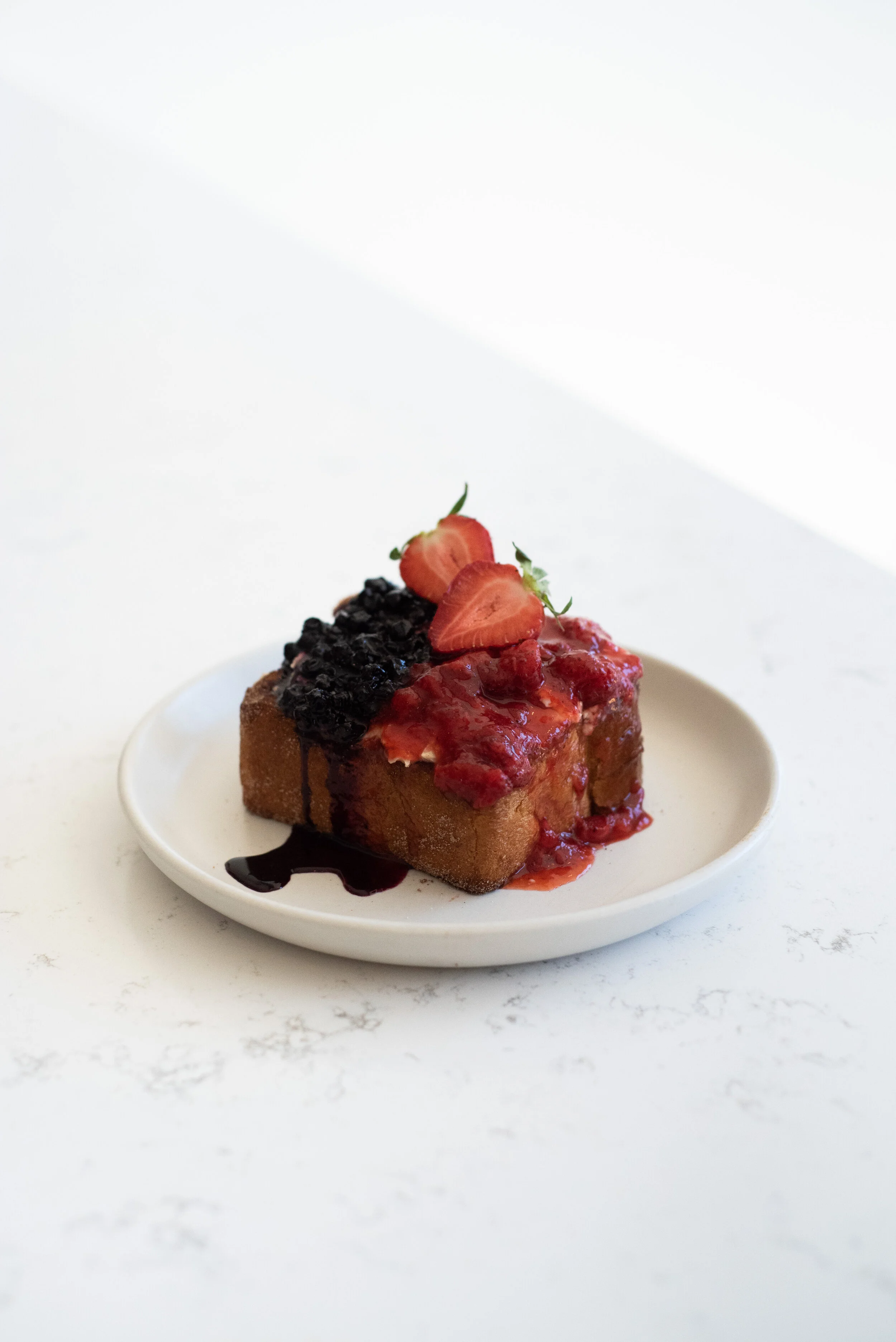 Thick-cut brioche French toast topped with fresh strawberry compote and blueberries..jpg
