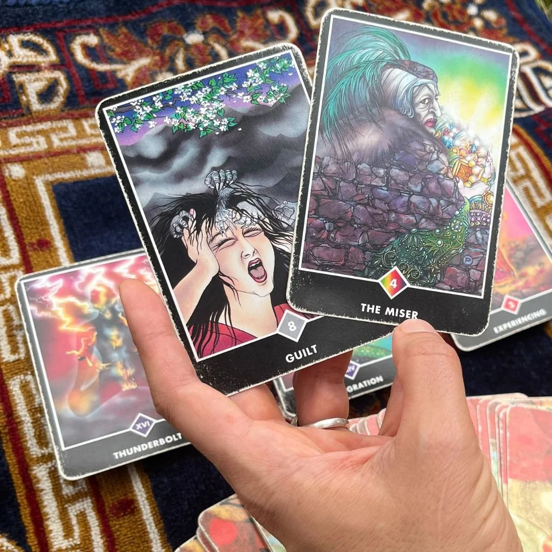 How to read tarot cards - a hand holding the miser and guilt cards from the zen tarot deck