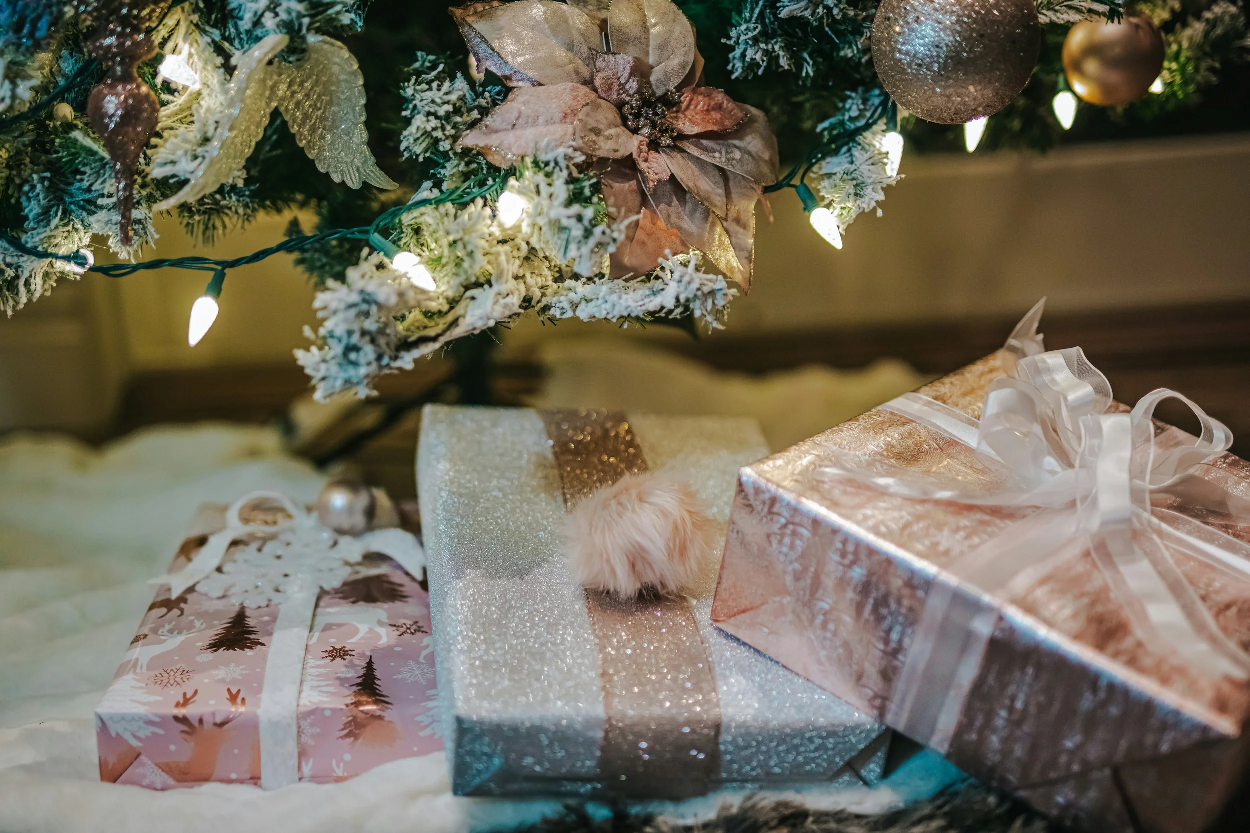 Pink Christmas gifts under a frosted tree with lights