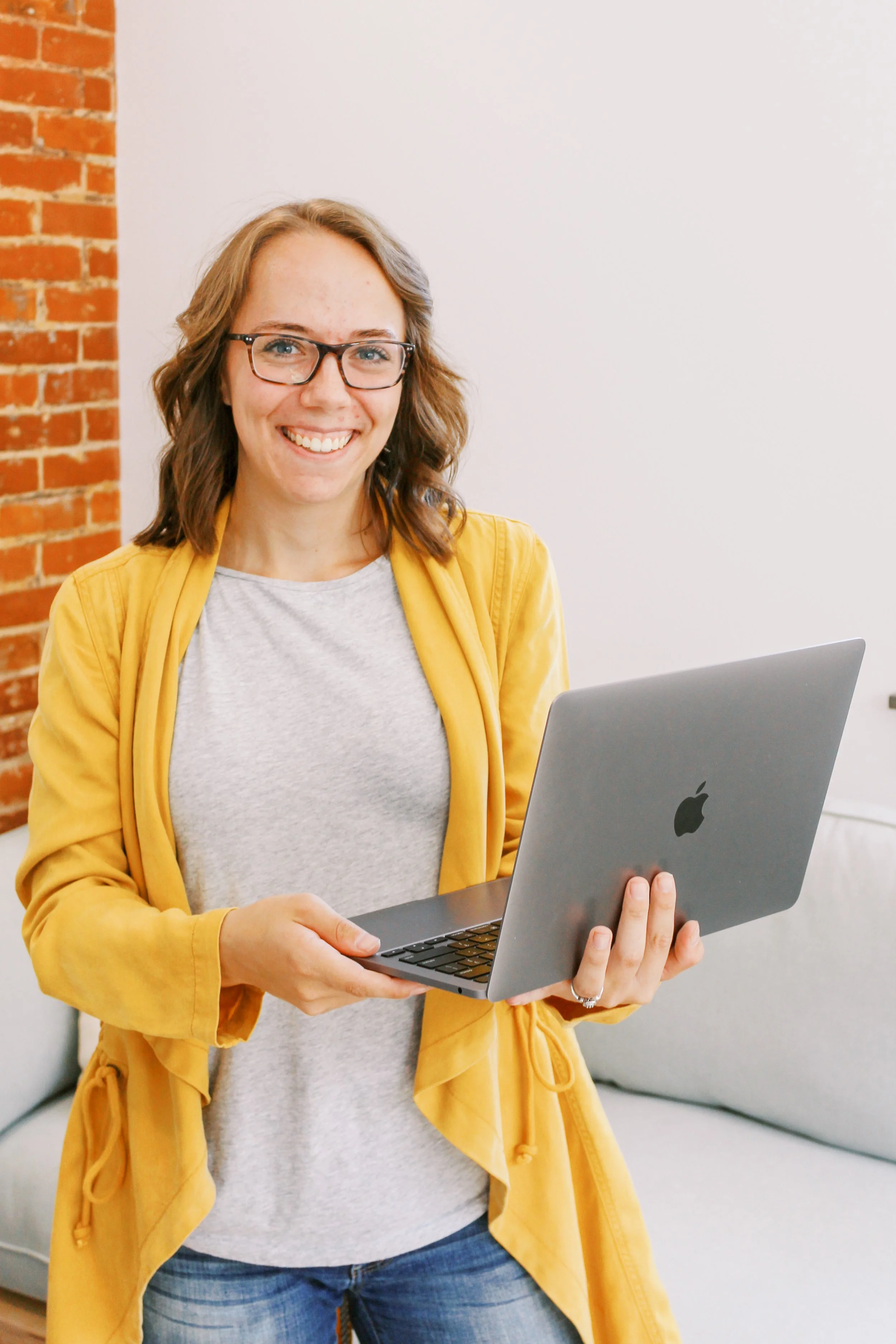 Elizabeth Wood of Elizabeth Wood Illustrates holding a laptop in her creative workspace.