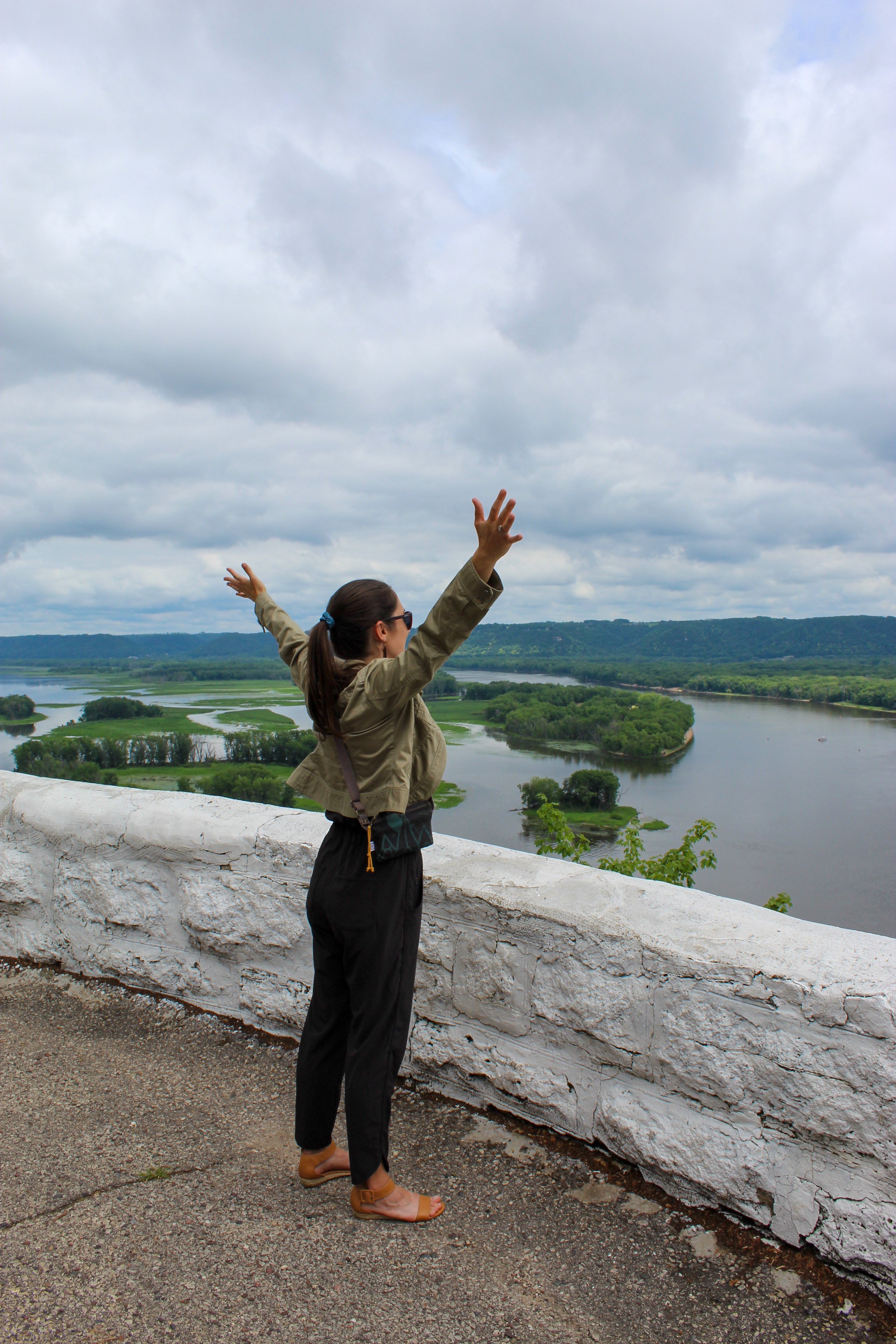  Life coach branding photos by wood media in lansing ia - a girl with her hands up looking over the mississippi river at mount hosmer in lansing ia 