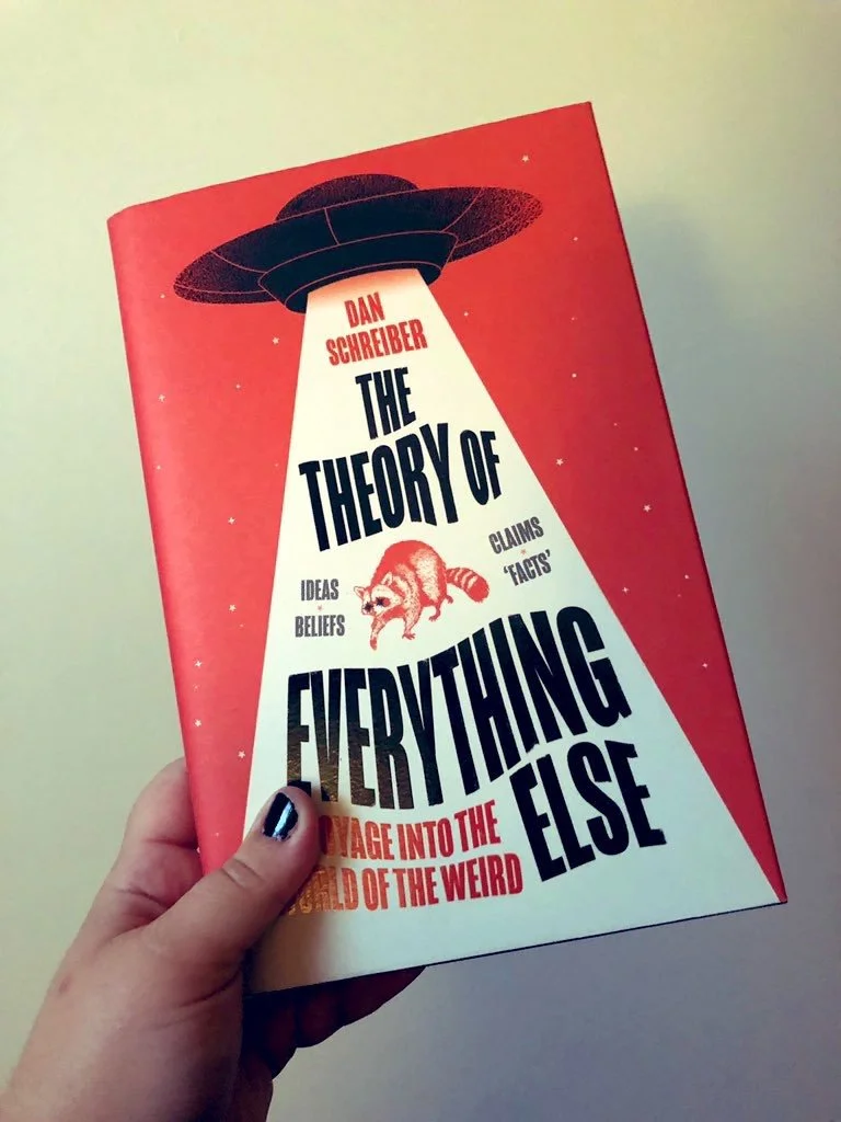 Kimberly's hand holds up a hardback copy of the UK release of Dan Schreiber's The Theory of Everything Else