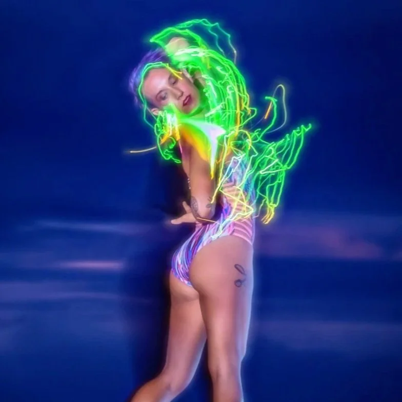 Educator, scholar and choreographer Maria Teresa Houar dances with an LED prop against a sunset background.