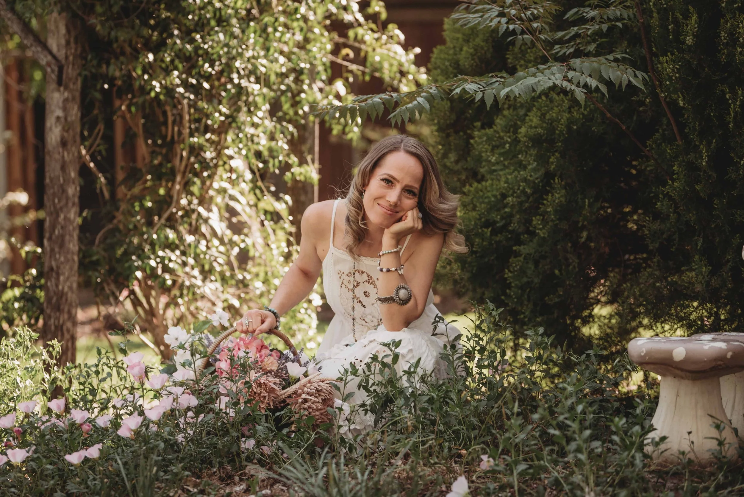 Cas, Toowoomba Reiki practitioner, crouching in a garden with a basket of flowers