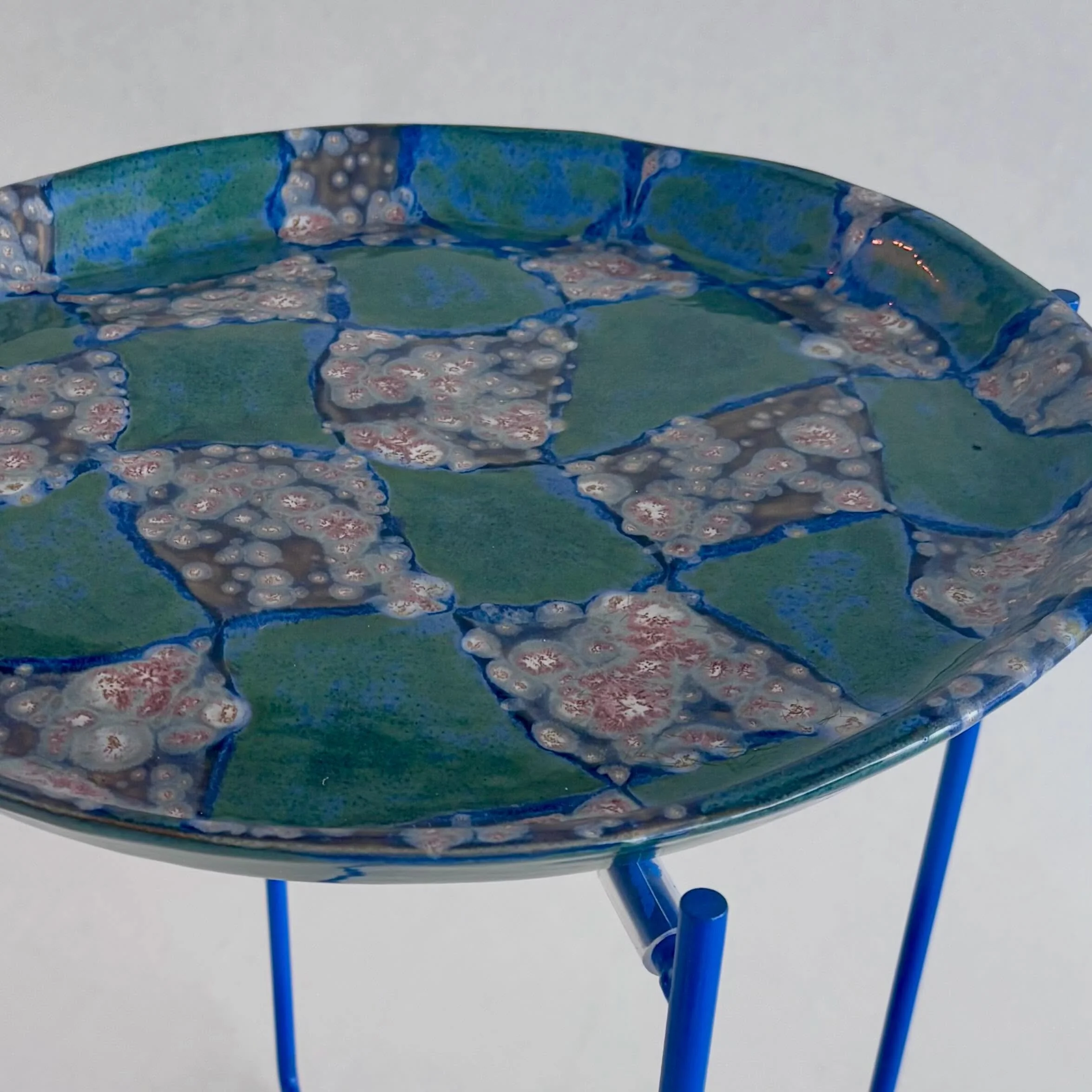 Stort fad i glaseret stent&oslash;j placeret p&aring; metalstel. P&aring; denne m&aring;de f&aring;r du det fineste bakkebord, og har stadig mulighed for at anvende fadet som v&aelig;gh&aelig;ngt kunst objekt eller som brugs objekt. 
Fadet er h&aring