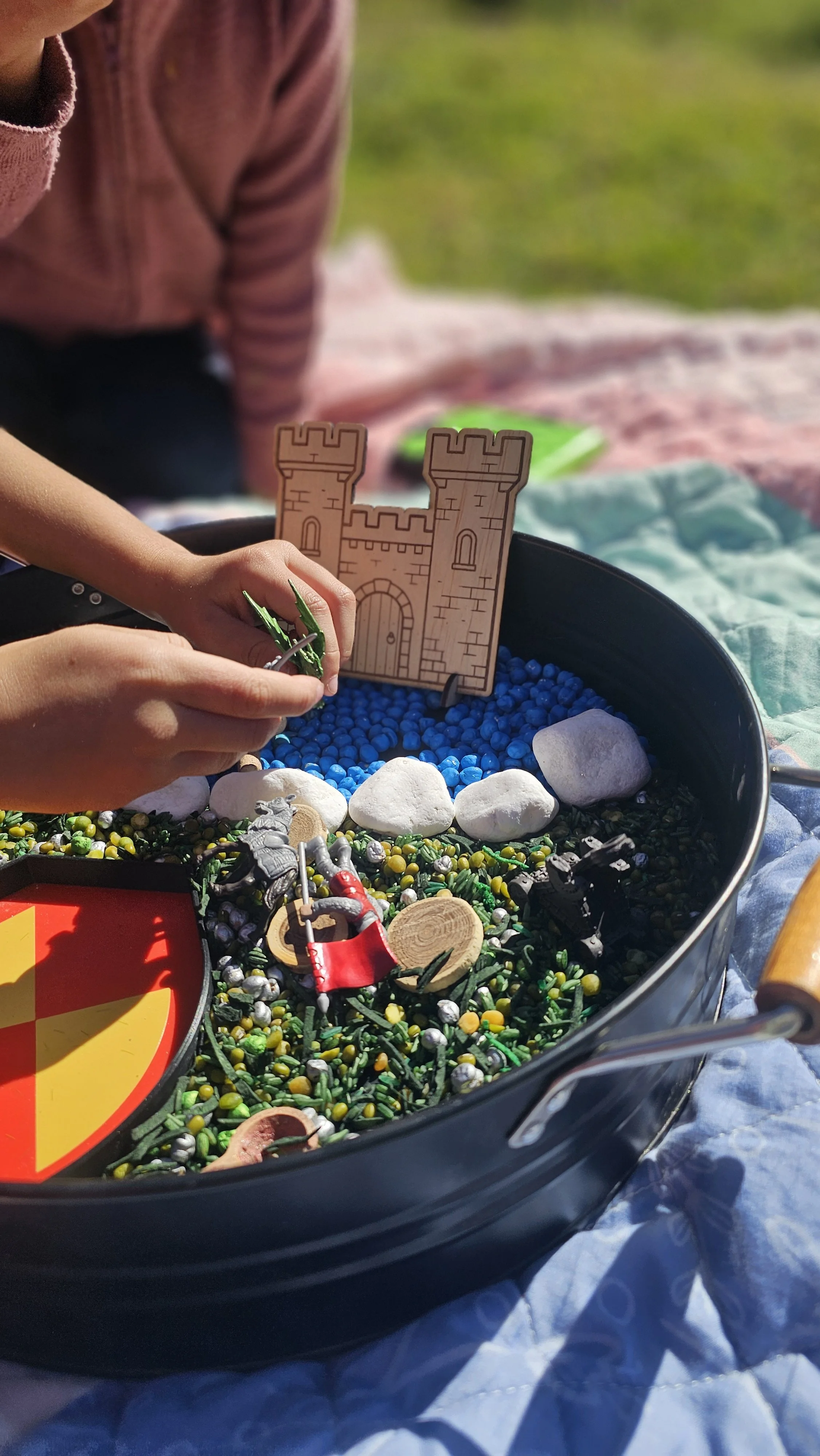 Children's castle sensory bin with knights and dragons.