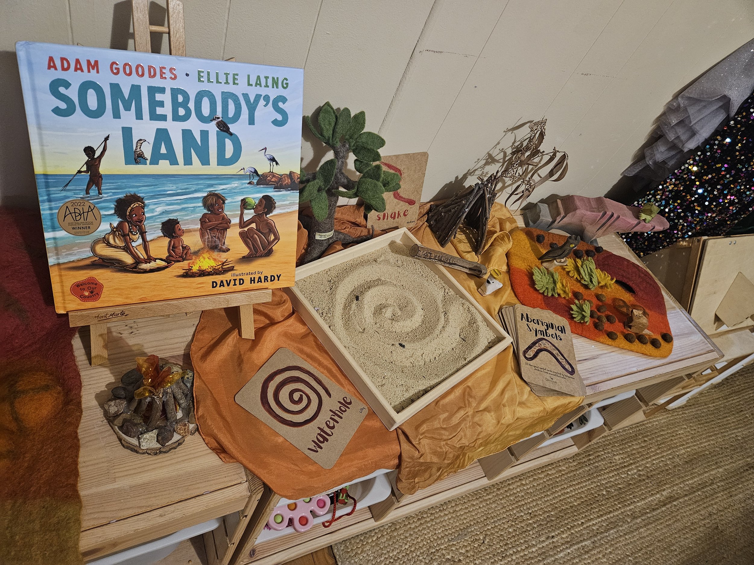 Child exploring a NAIDOC Week sensory tray with coloured rice, natural materials and Indigenous-inspired loose parts for hands-on learning.
