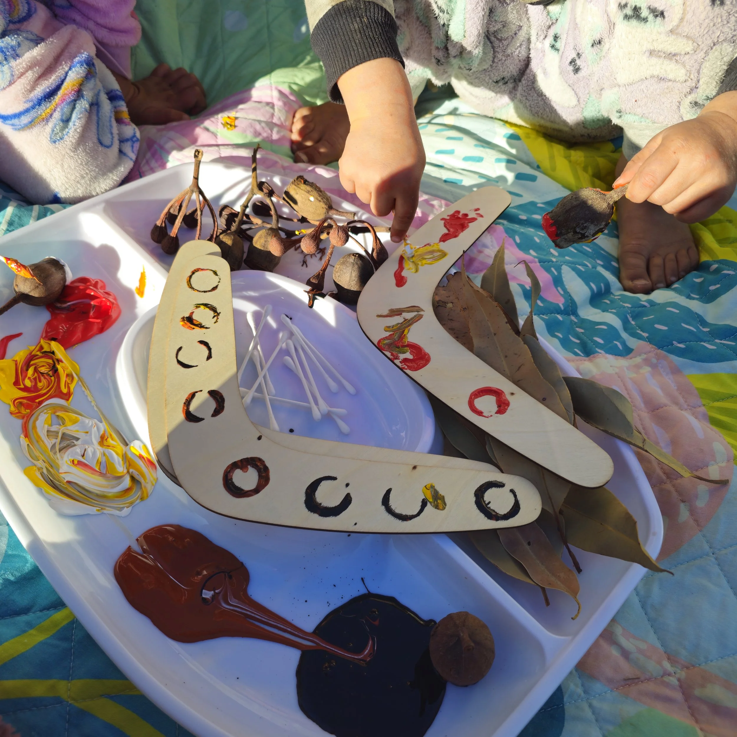 Child creating a NAIDOC Week inspired craft using natural materials, paint and hands-on creative exploration.